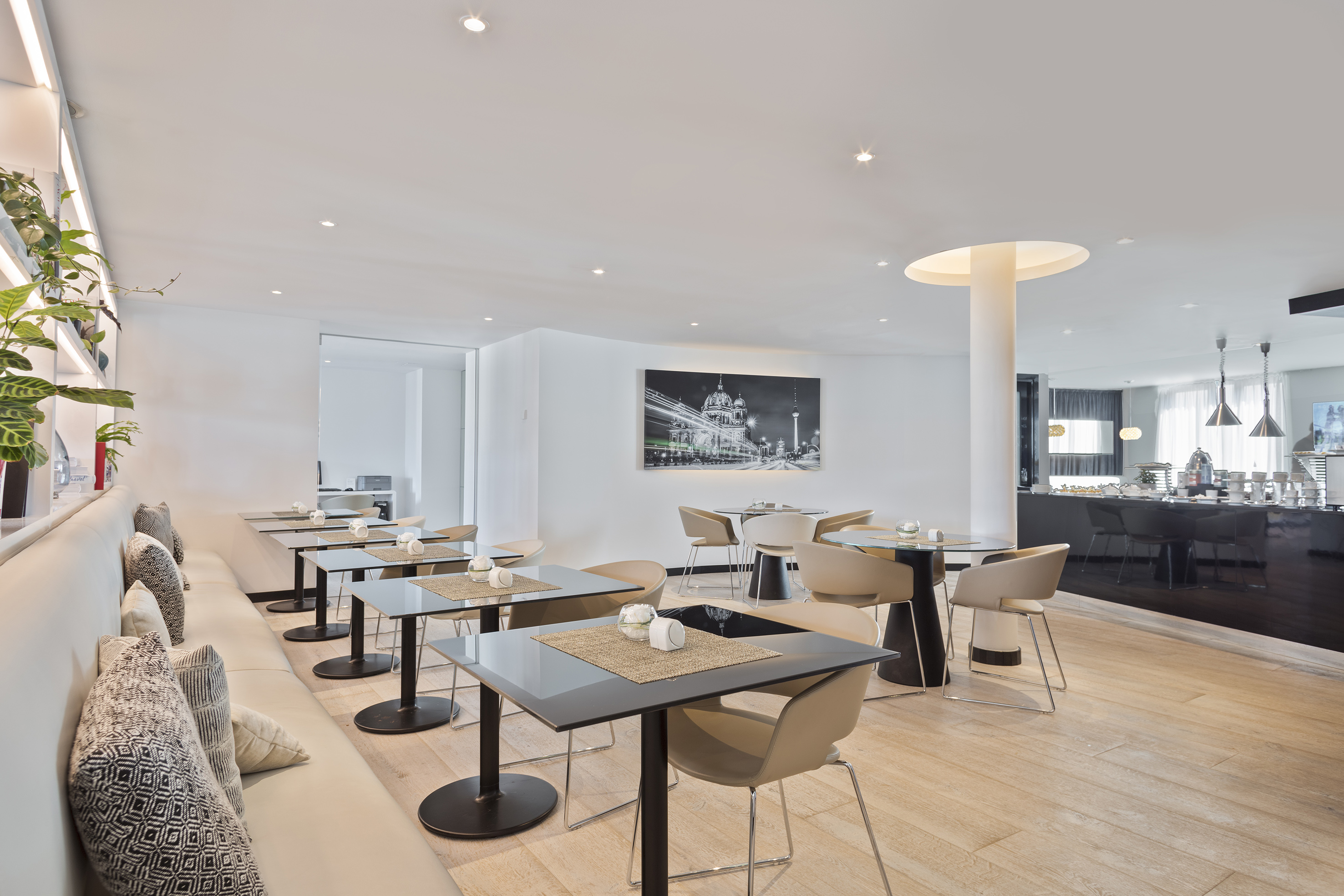 Modern cafe interior with banquette, black tables, and buffet area. - Nechte se unést světem výjimečnosti a exkluzivního vybavení. - Meliá Berlin, Berlín