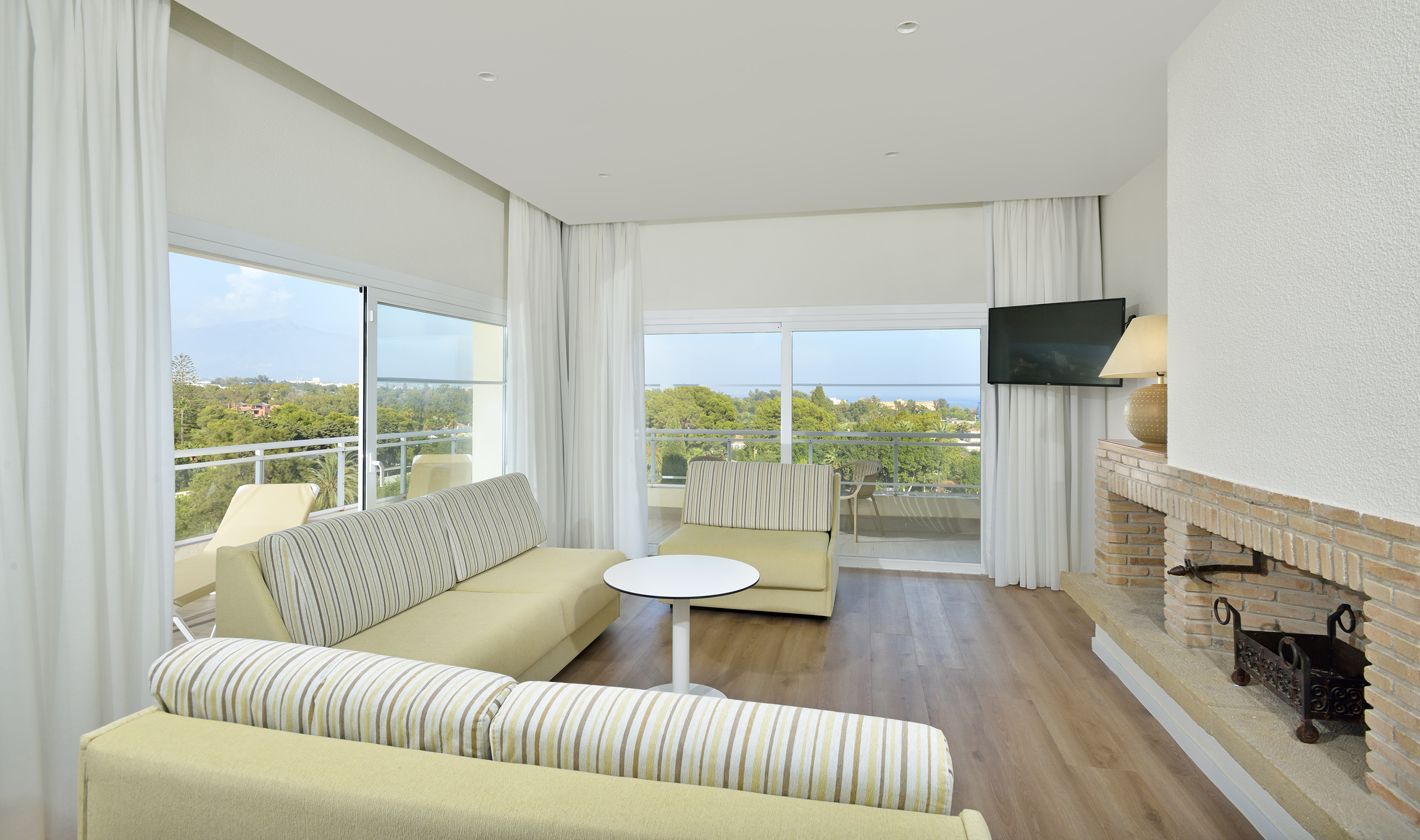 Modern hotel suite living room with sea view balcony.