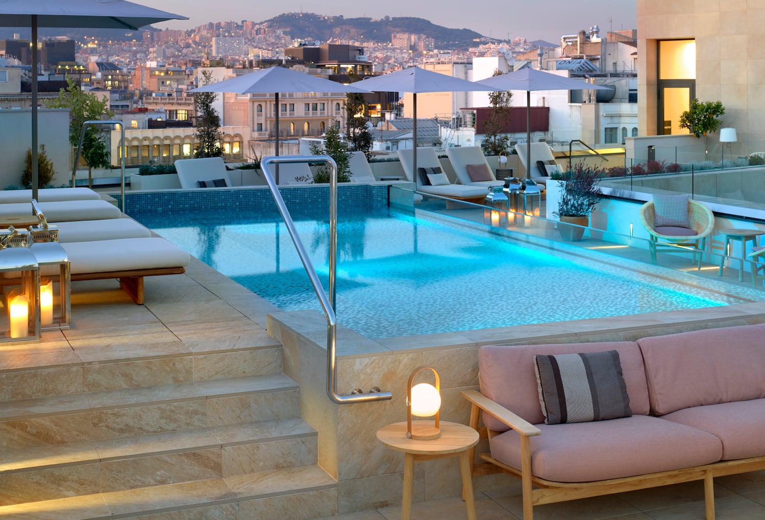 a pool with chairs and umbrellas on a rooftop