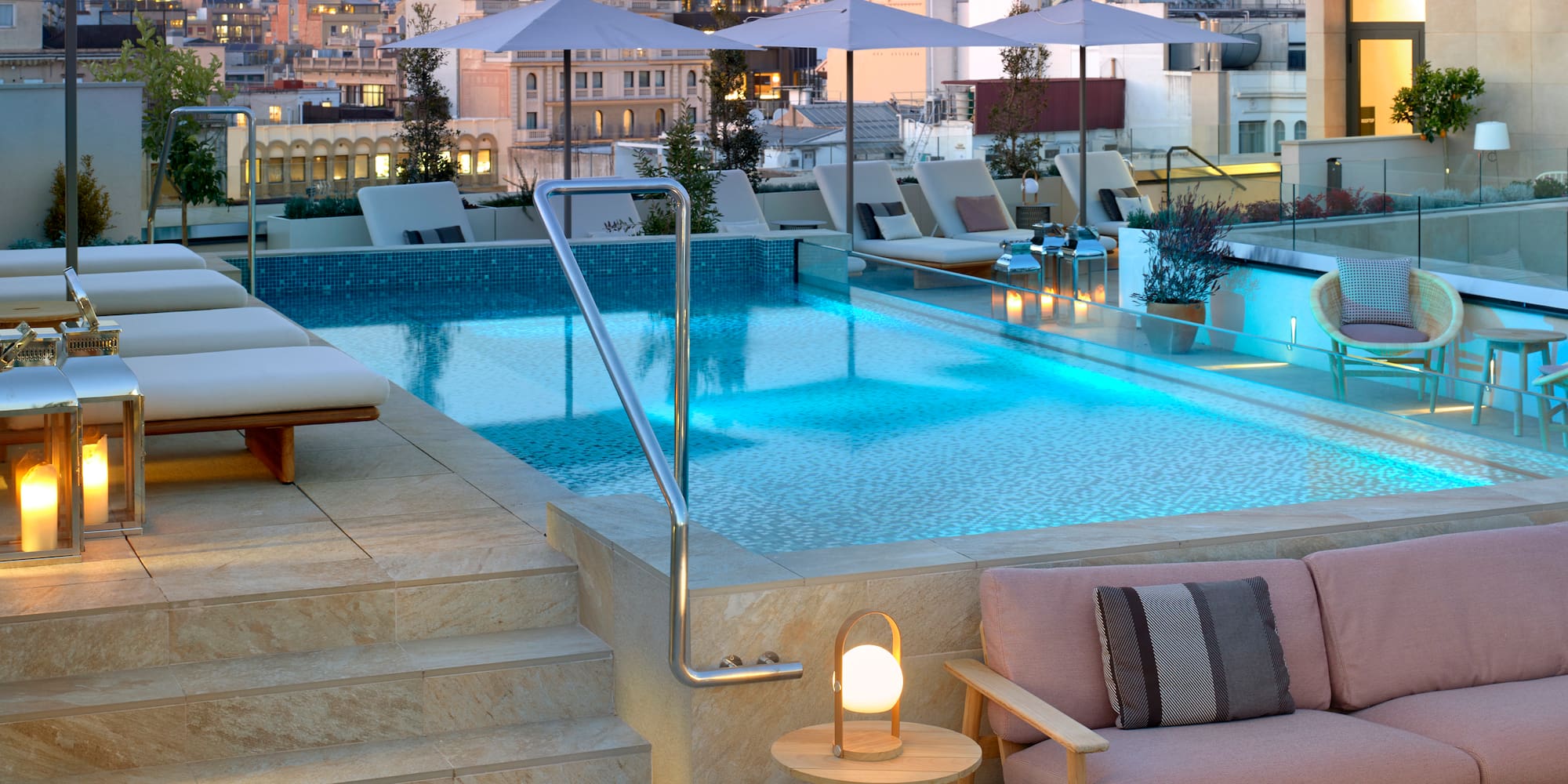 a pool with chairs and umbrellas on a rooftop