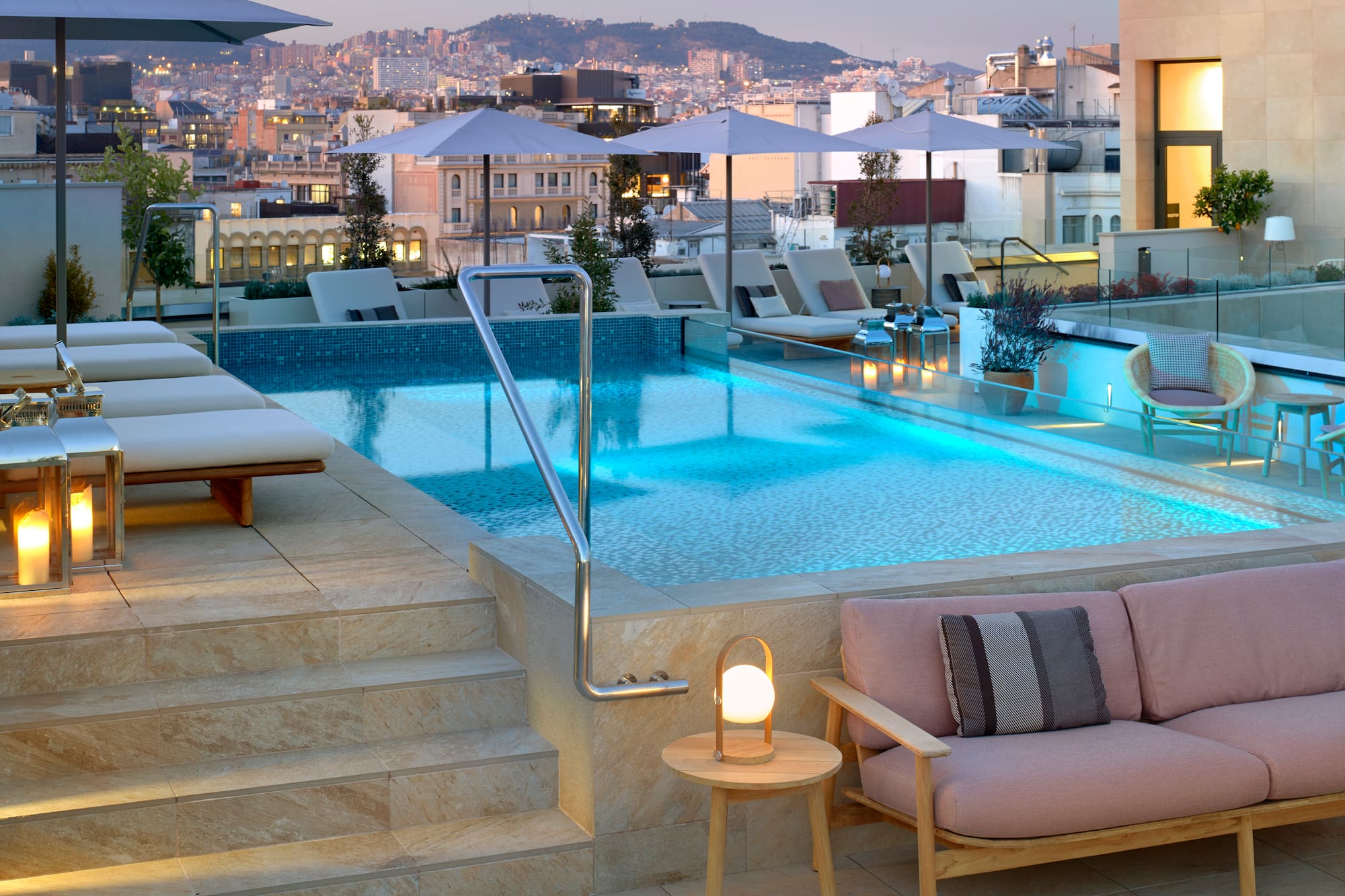 a pool with chairs and umbrellas on a rooftop