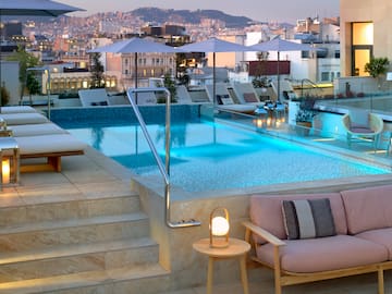 a pool with chairs and umbrellas on a rooftop