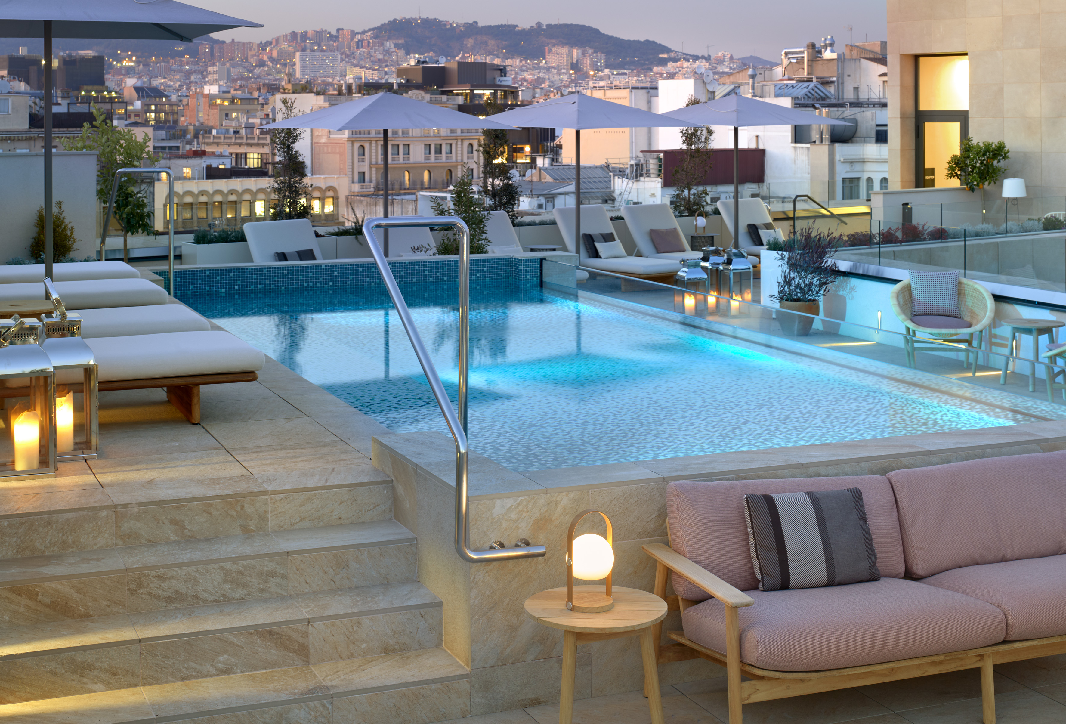 a pool with chairs and umbrellas on a rooftop