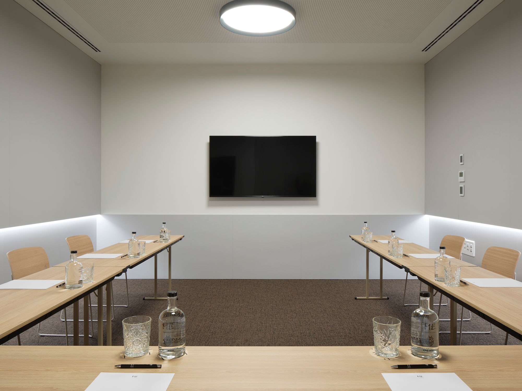 a room with tables and chairs and a television on the wall