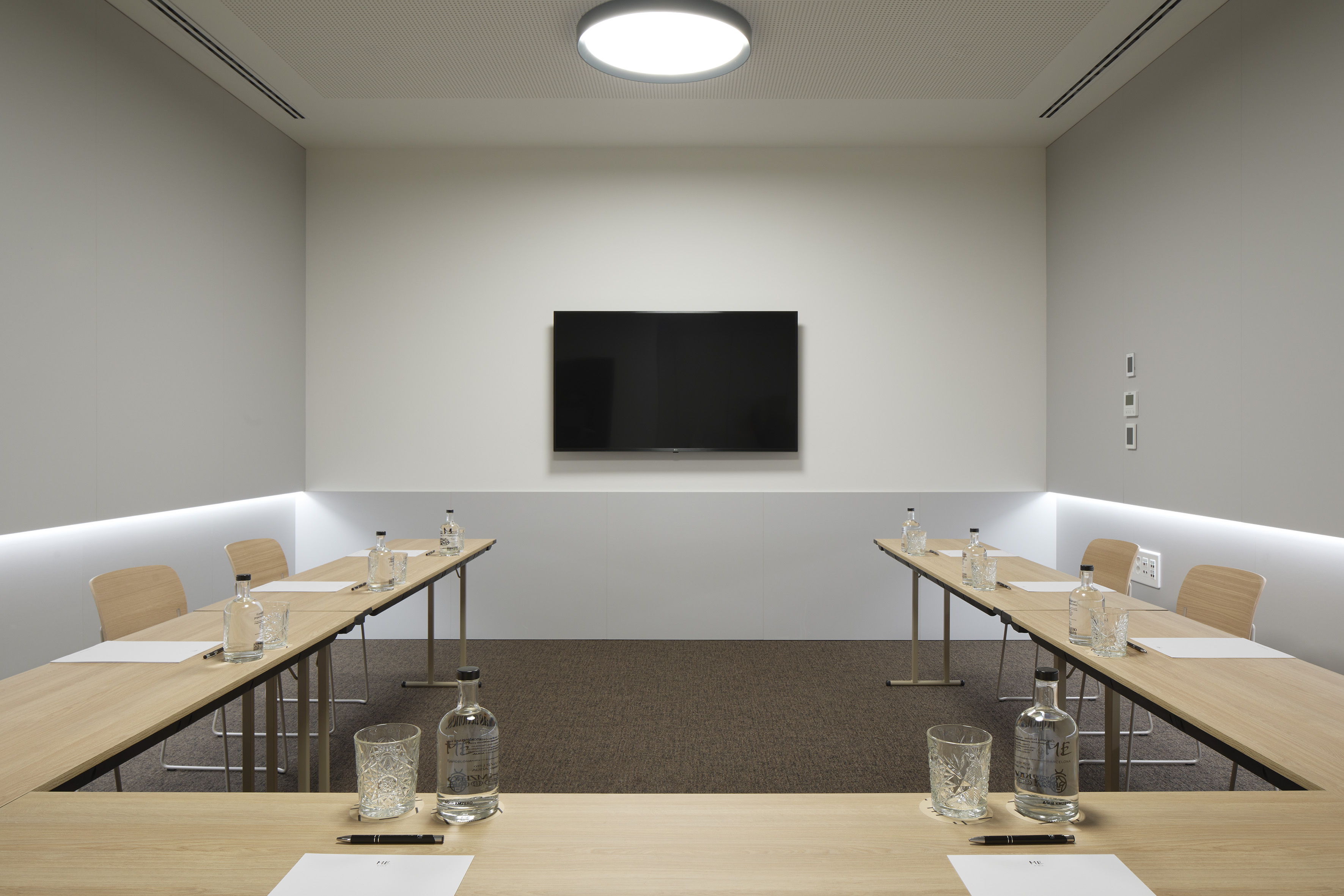 a room with tables and chairs and a television on the wall