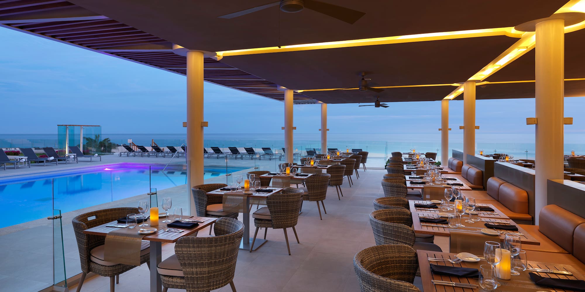 a restaurant with tables and chairs by a pool