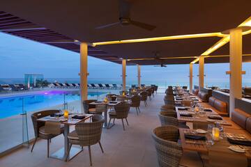 a restaurant with tables and chairs by a pool