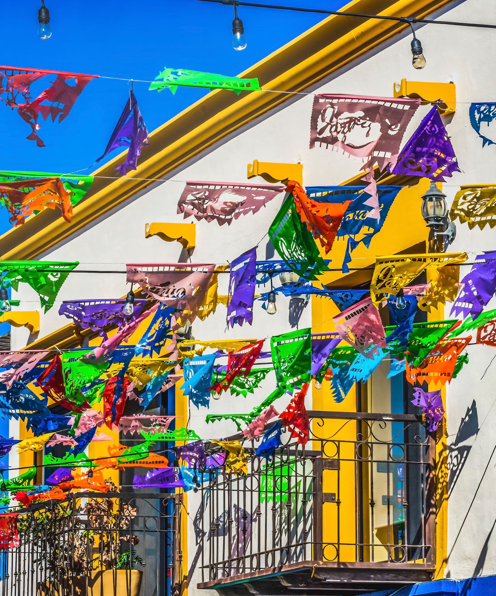 Banderines de papel picado coloridos en calle mexicana festiva.