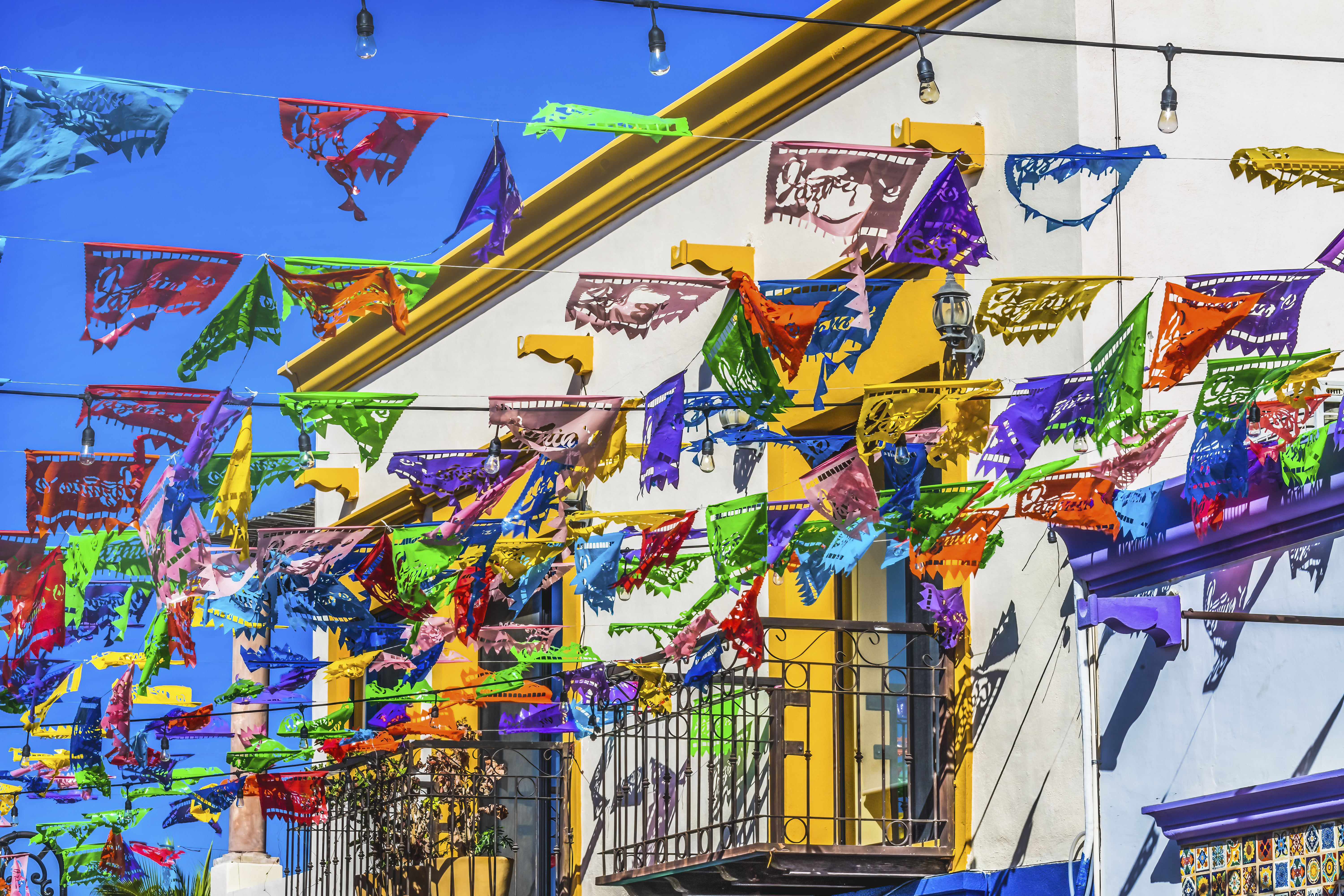 Banderines de papel picado coloridos en calle mexicana festiva.