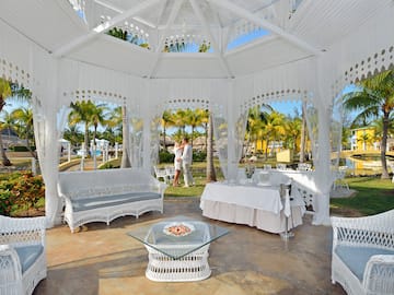 a white gazebo with white curtains and tables and chairs