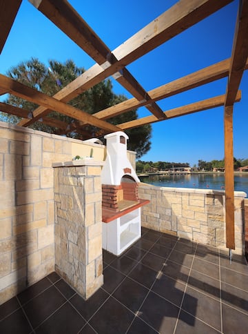 a stone patio with a wood roof over a lake