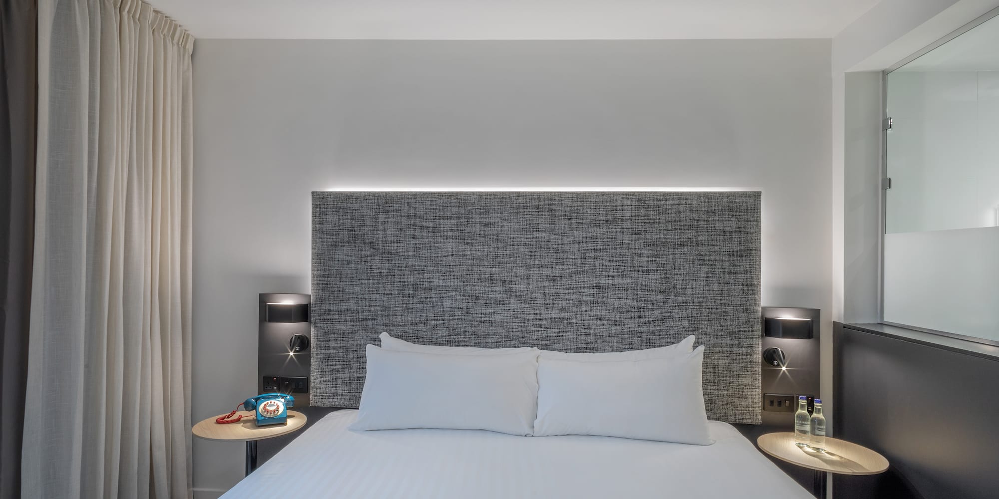 a bed with a headboard and a table with a lamp