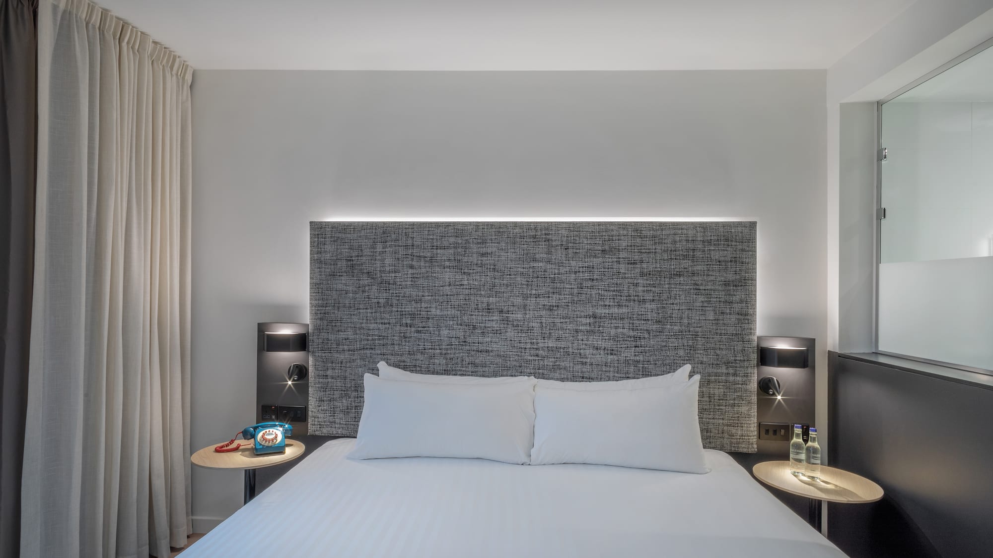 a bed with a headboard and a table with a lamp