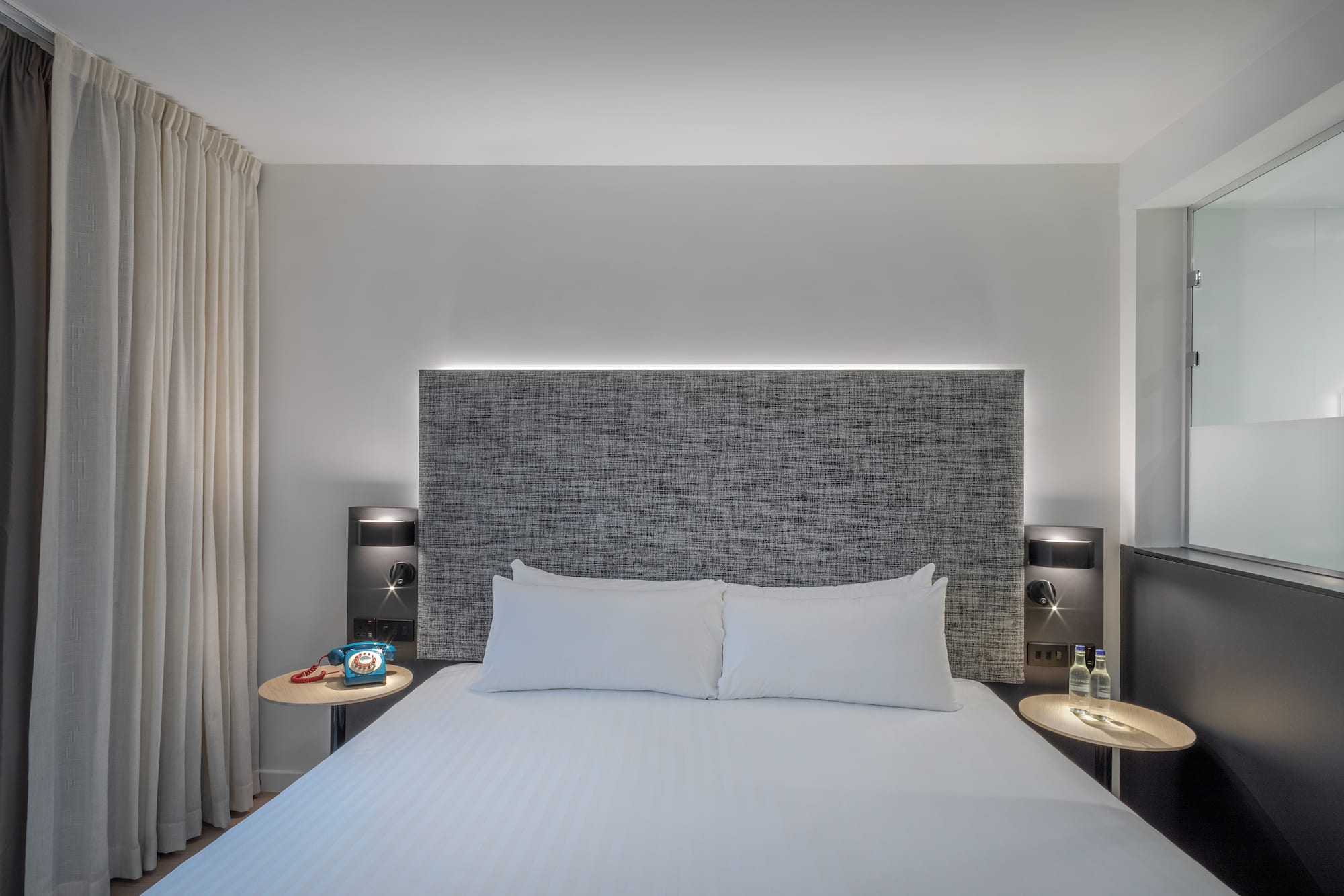 a bed with a headboard and a table with a lamp