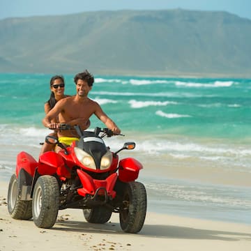 a man and woman on a quad bike on a beach