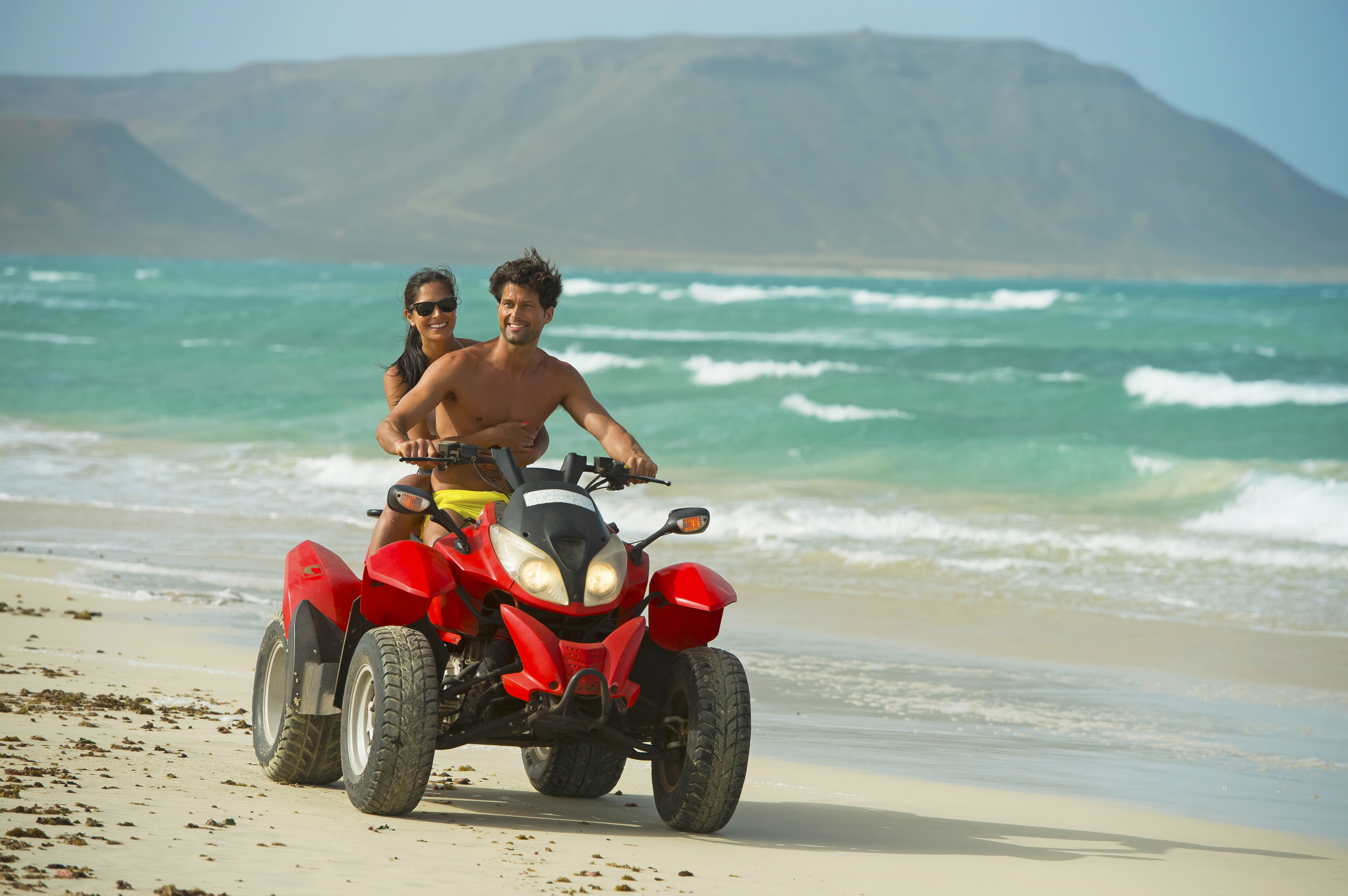 a man and woman on a quad bike on a beach
