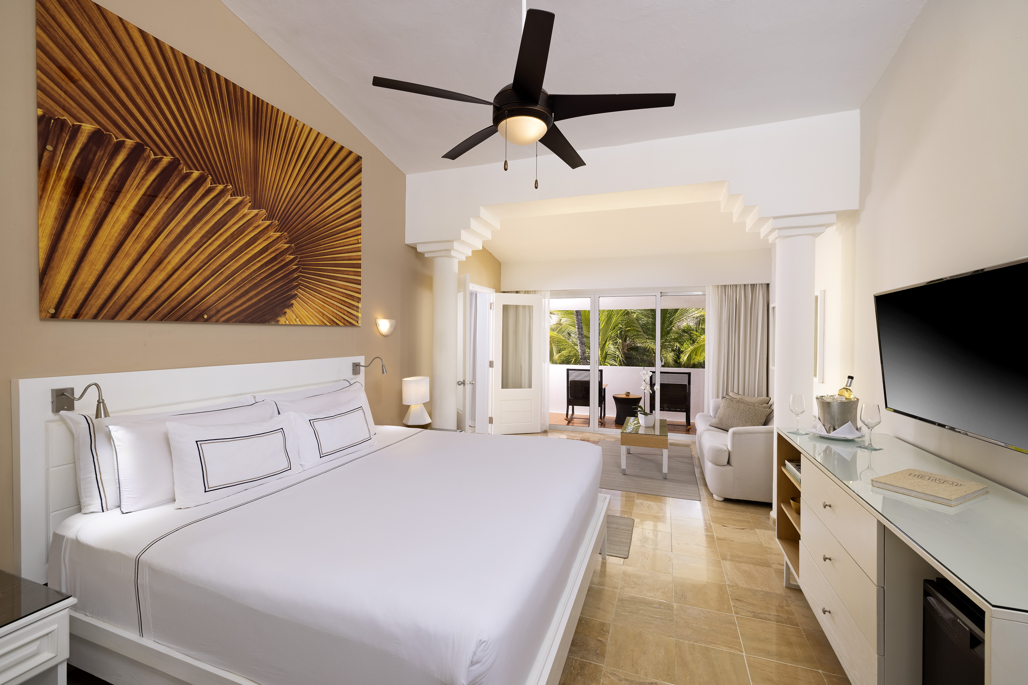 Elegant tropical resort room with king bed, private balcony, and modern design.