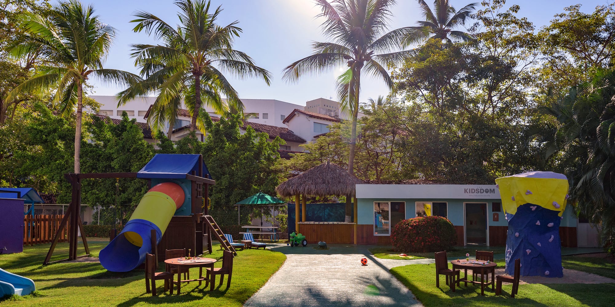 a playground with a slide and chairs in the middle of a yard