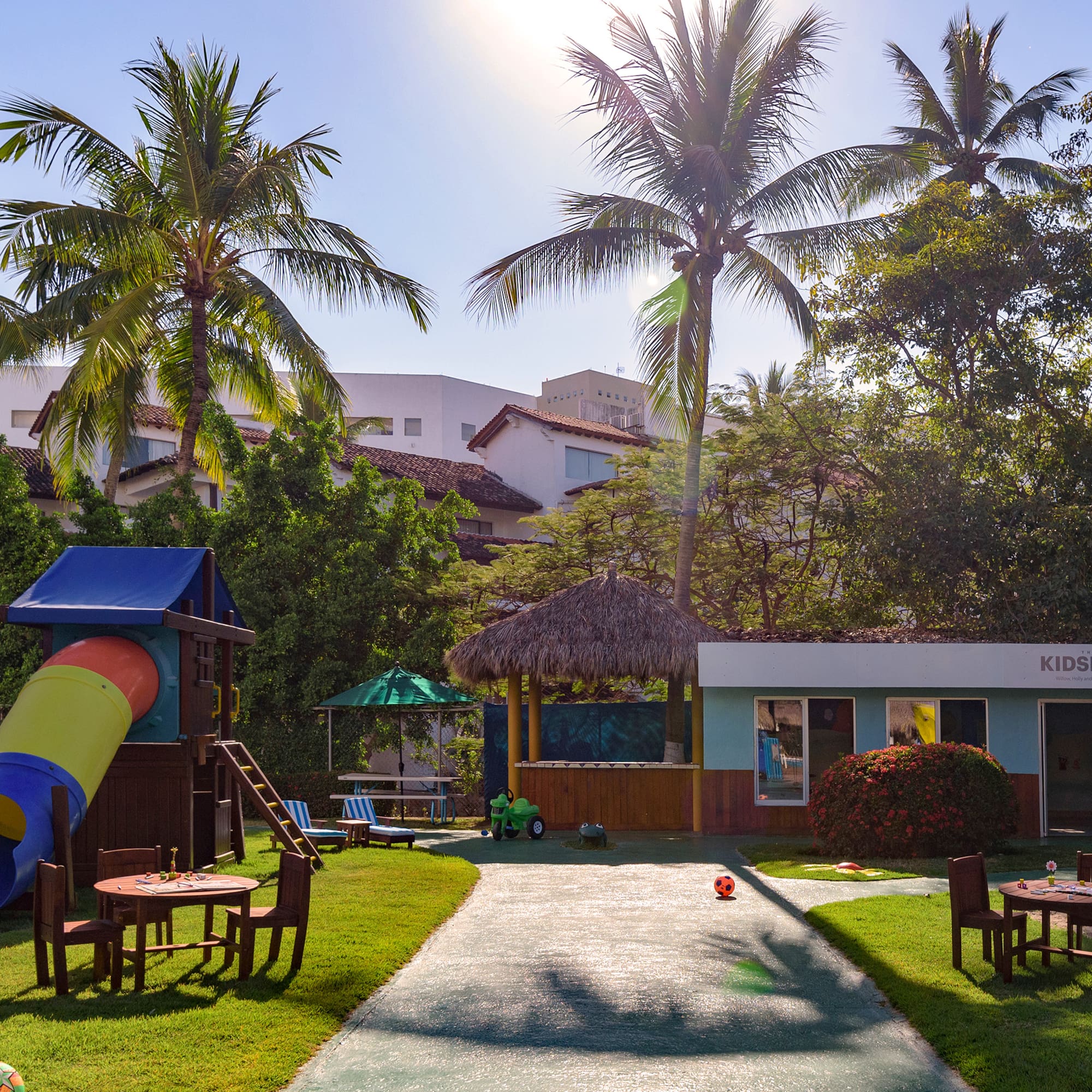 a playground with a slide and chairs in the middle of a yard
