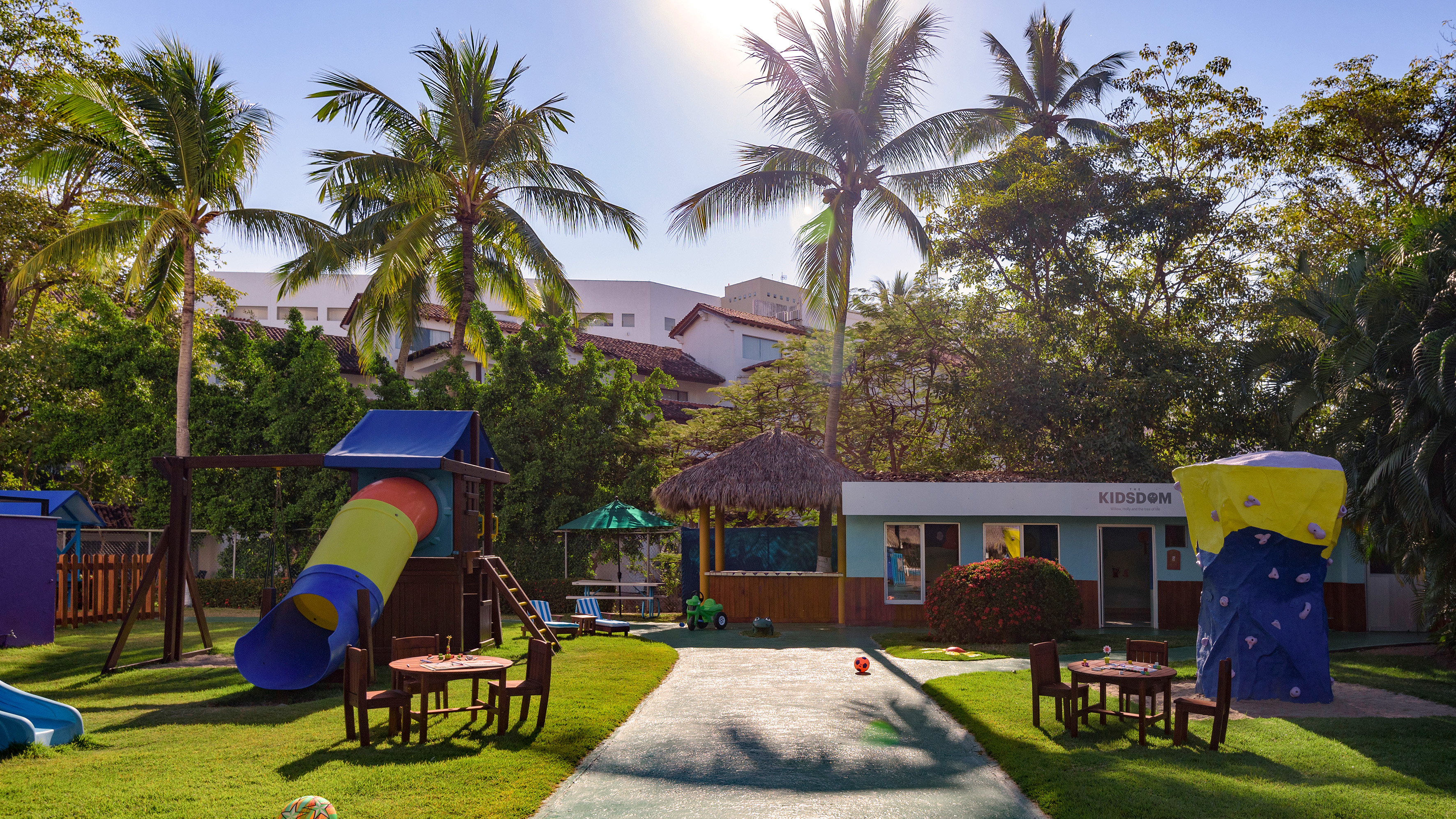 a playground with a slide and chairs in the middle of a yard