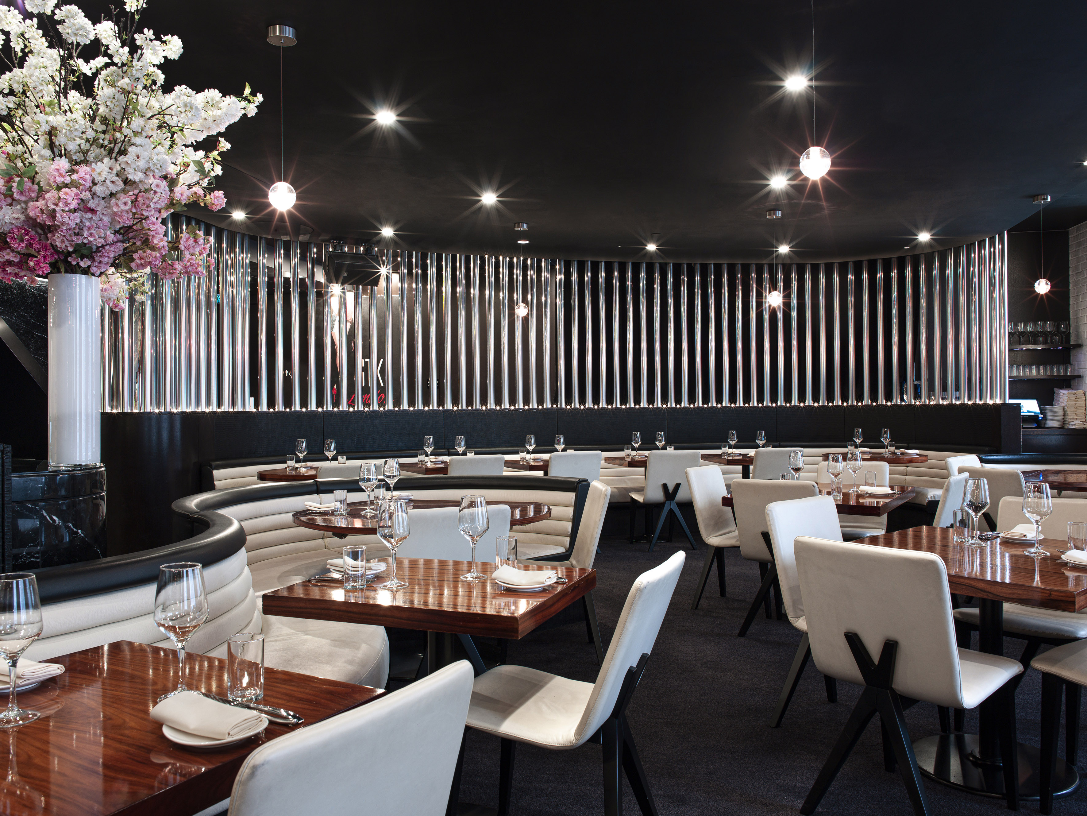Elegant modern restaurant dining room with curved banquettes and wooden tables.