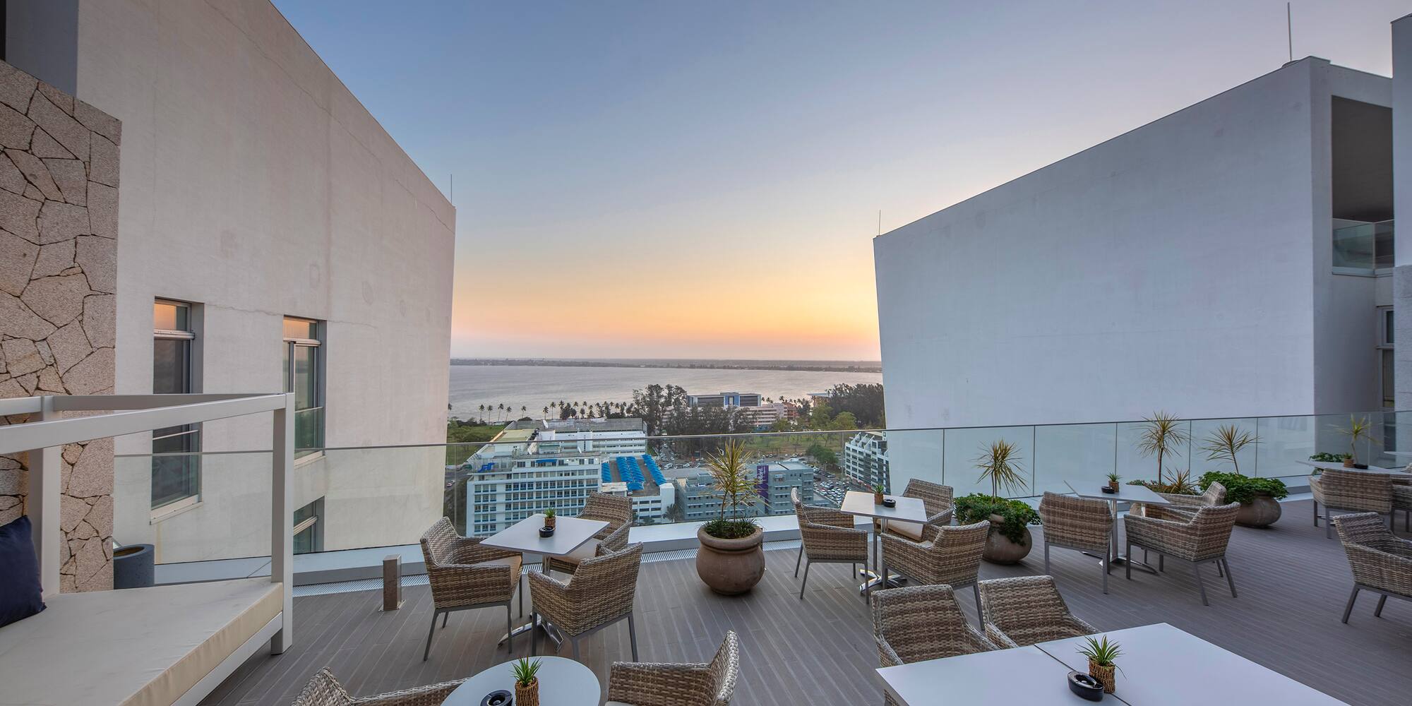 a patio with tables and chairs on a deck with a view of the ocean