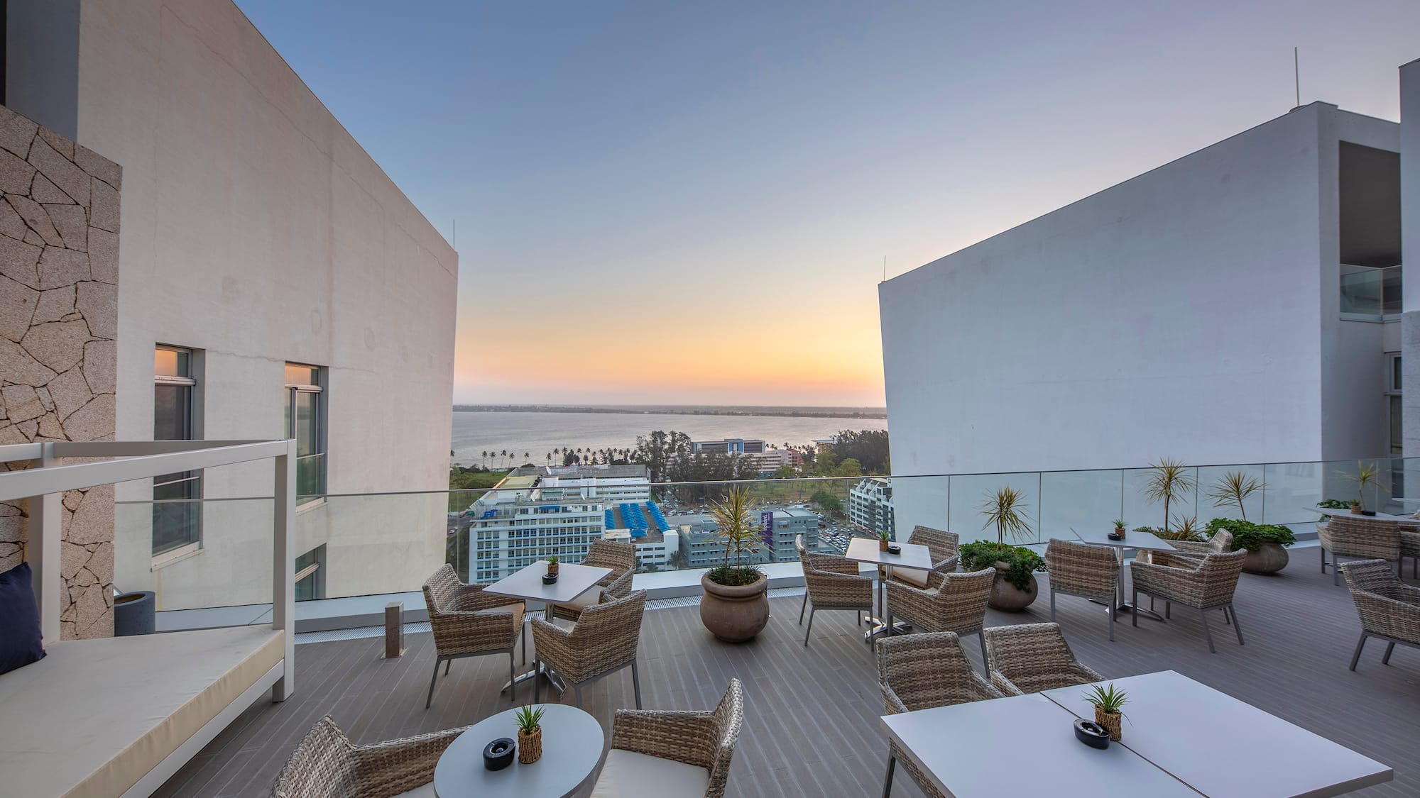 a patio with tables and chairs on a deck with a view of the ocean