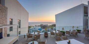 a patio with tables and chairs on a deck with a view of the ocean