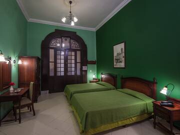 a room with green walls and a bed and a table