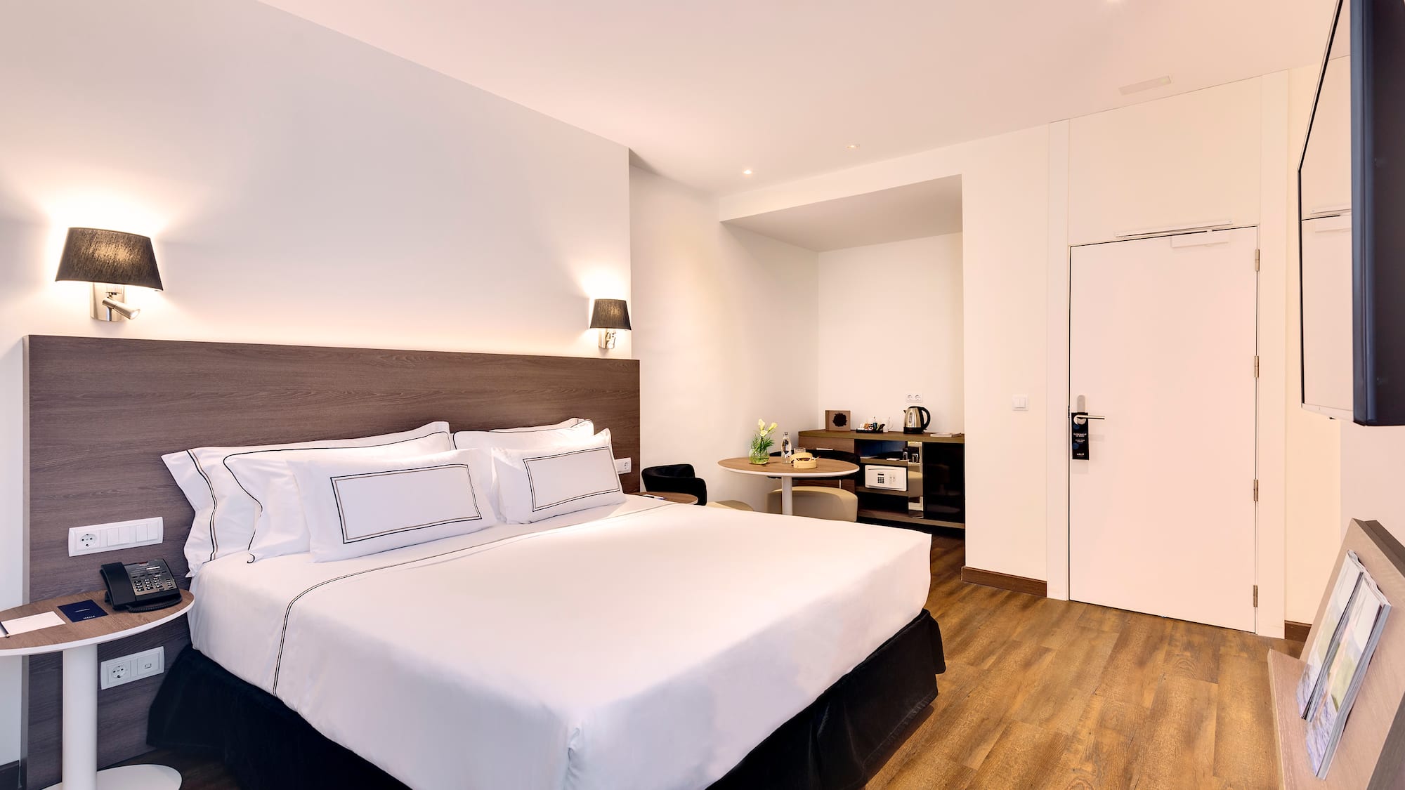 a bed with white sheets and a wood floor