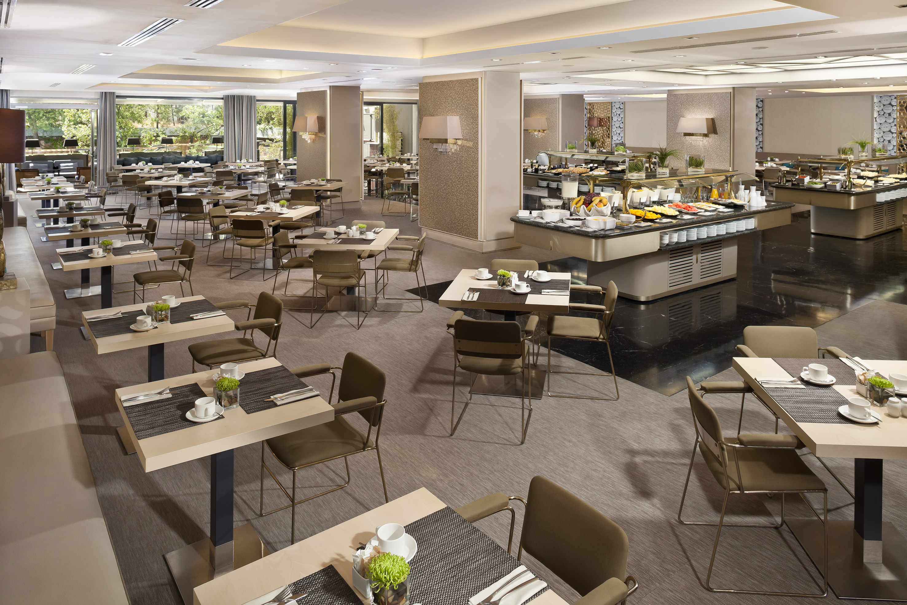 Modern hotel restaurant dining room with a breakfast buffet and outdoor view.