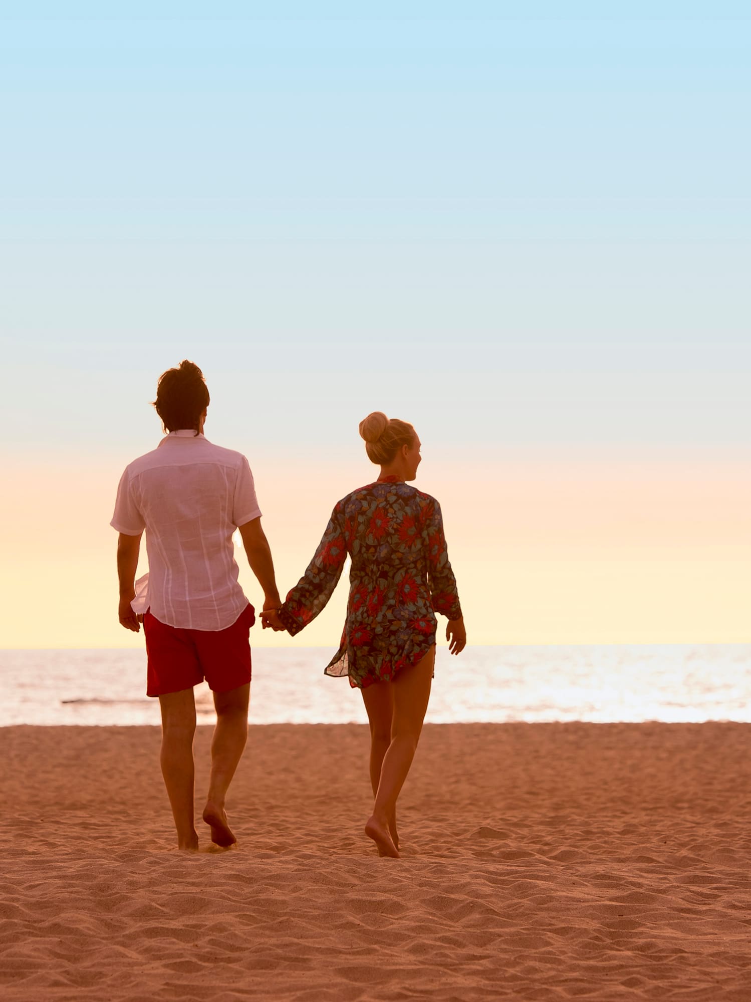 a man and woman holding hands on a beach