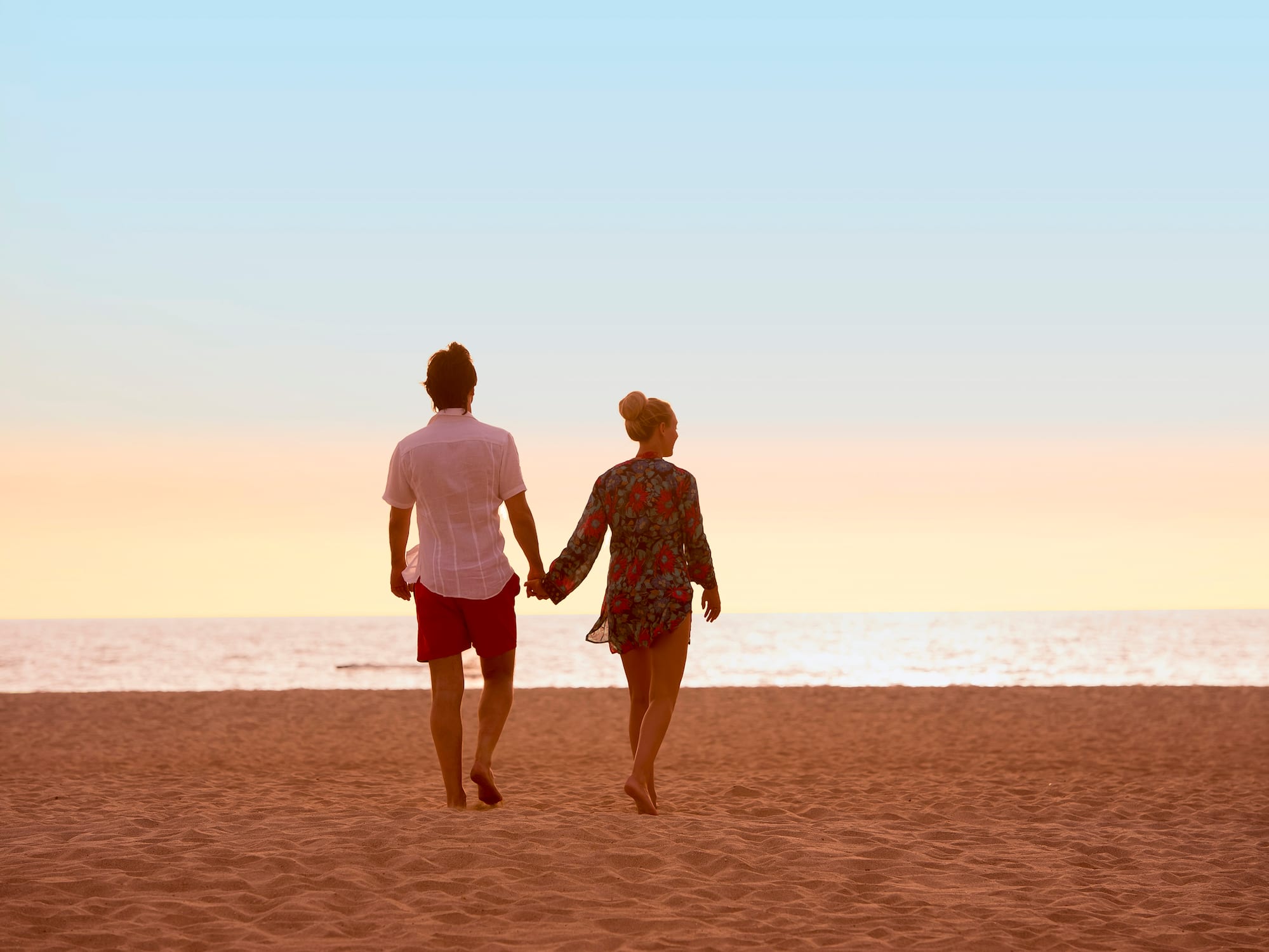 a man and woman holding hands on a beach