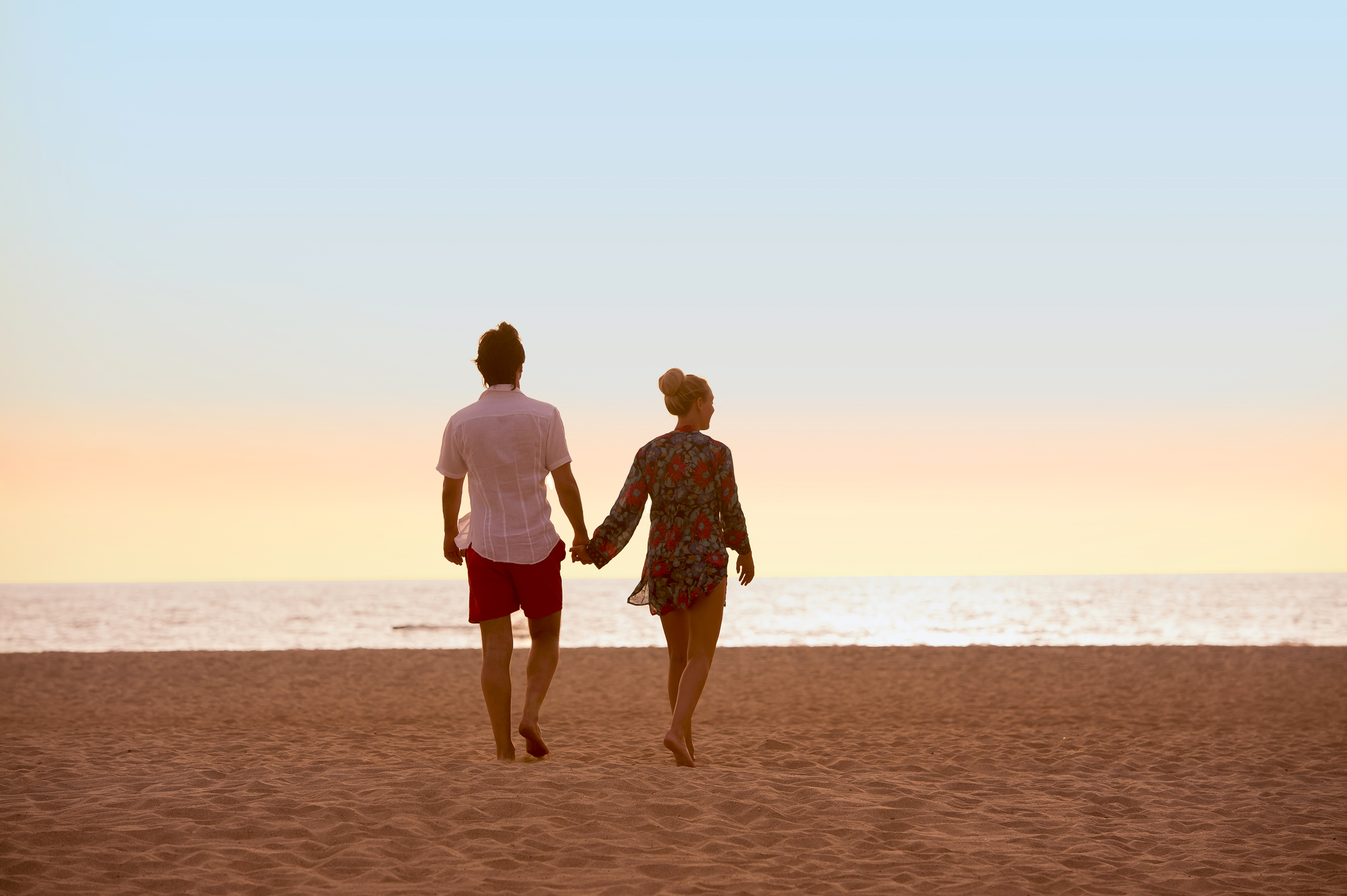 a man and woman holding hands on a beach