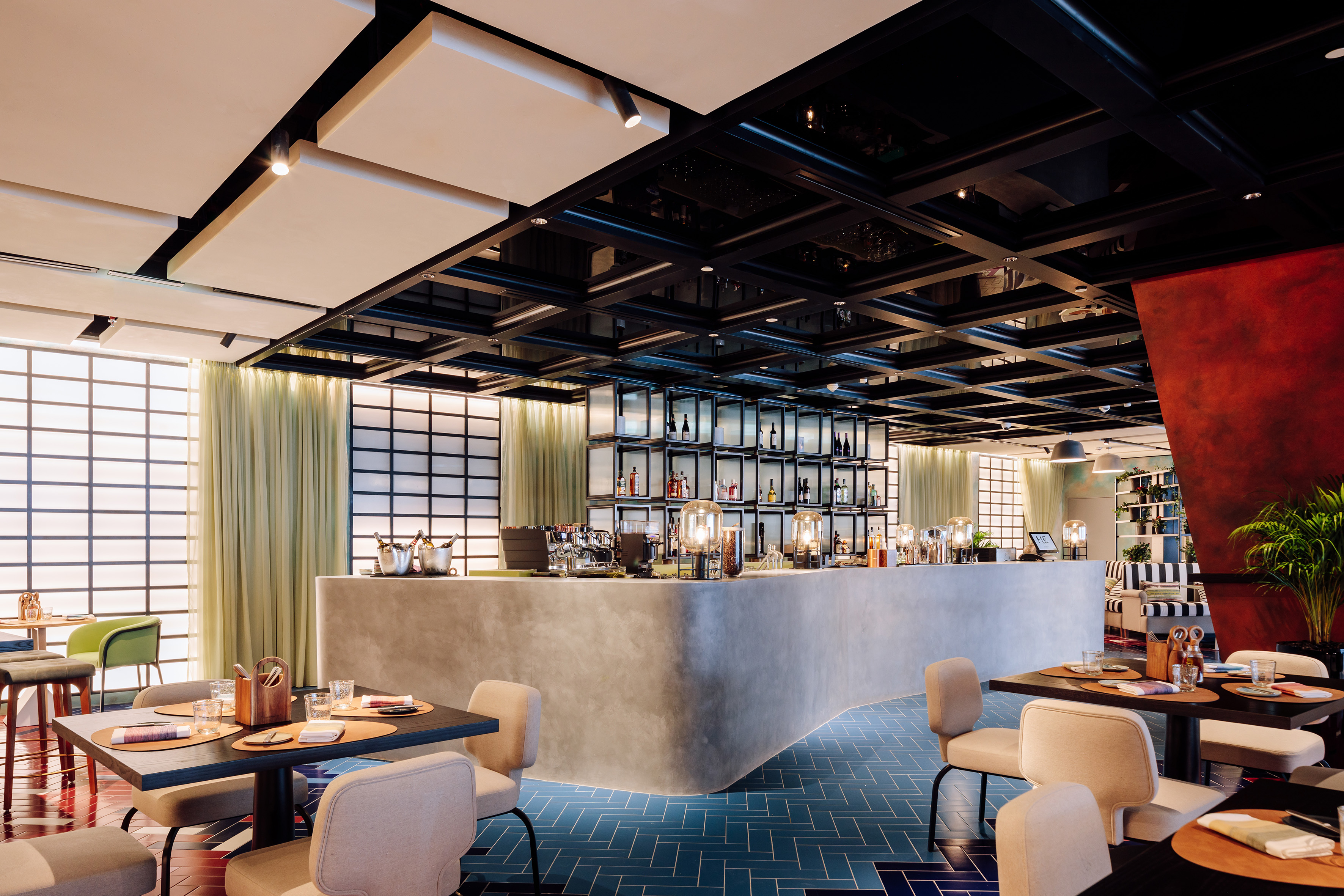 Modern restaurant bar interior with concrete counter, blue tile floor, and dining tables.