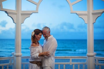 a man and woman standing on a porch with water in the background