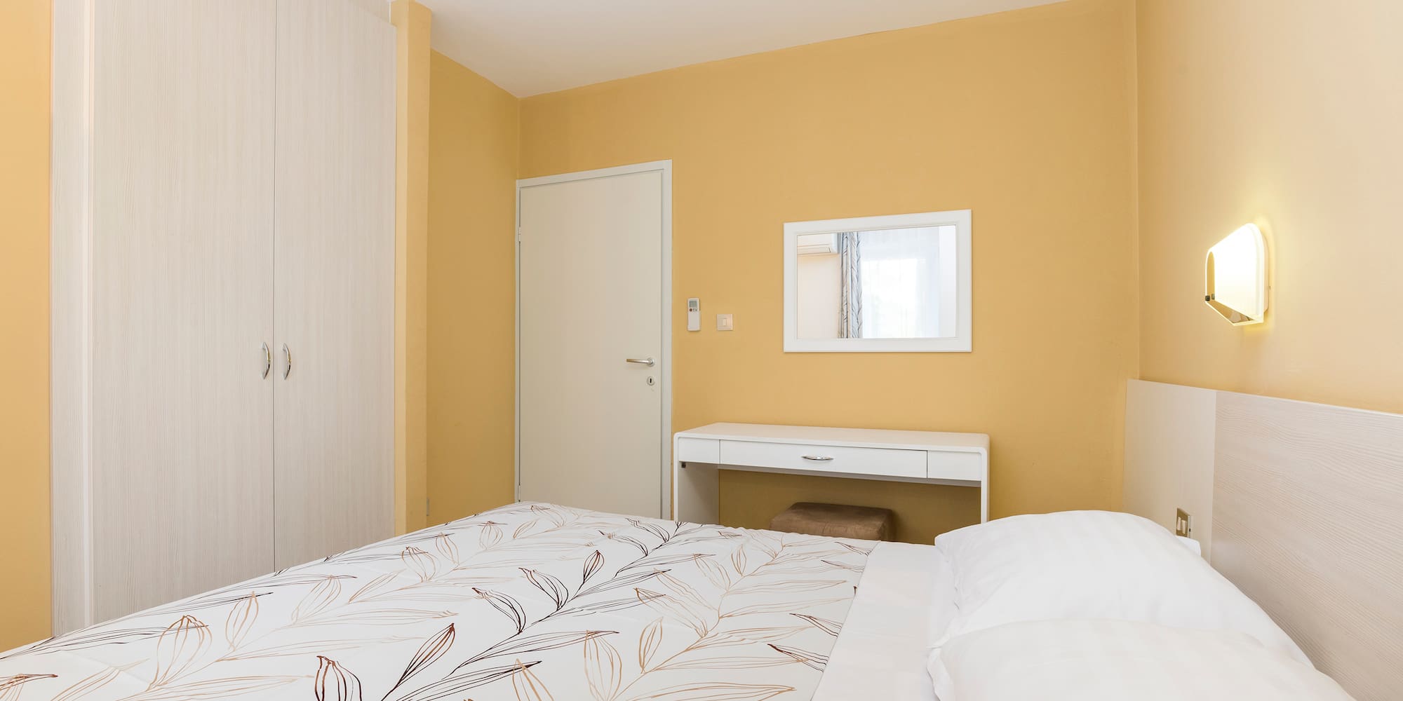 a bed with a white bedding and a mirror in a room