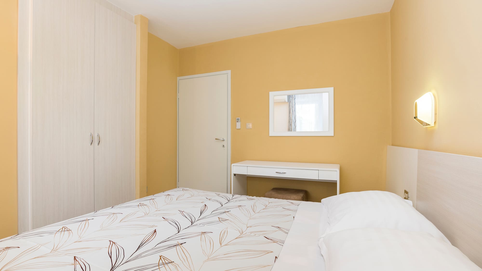 a bed with a white bedding and a mirror in a room