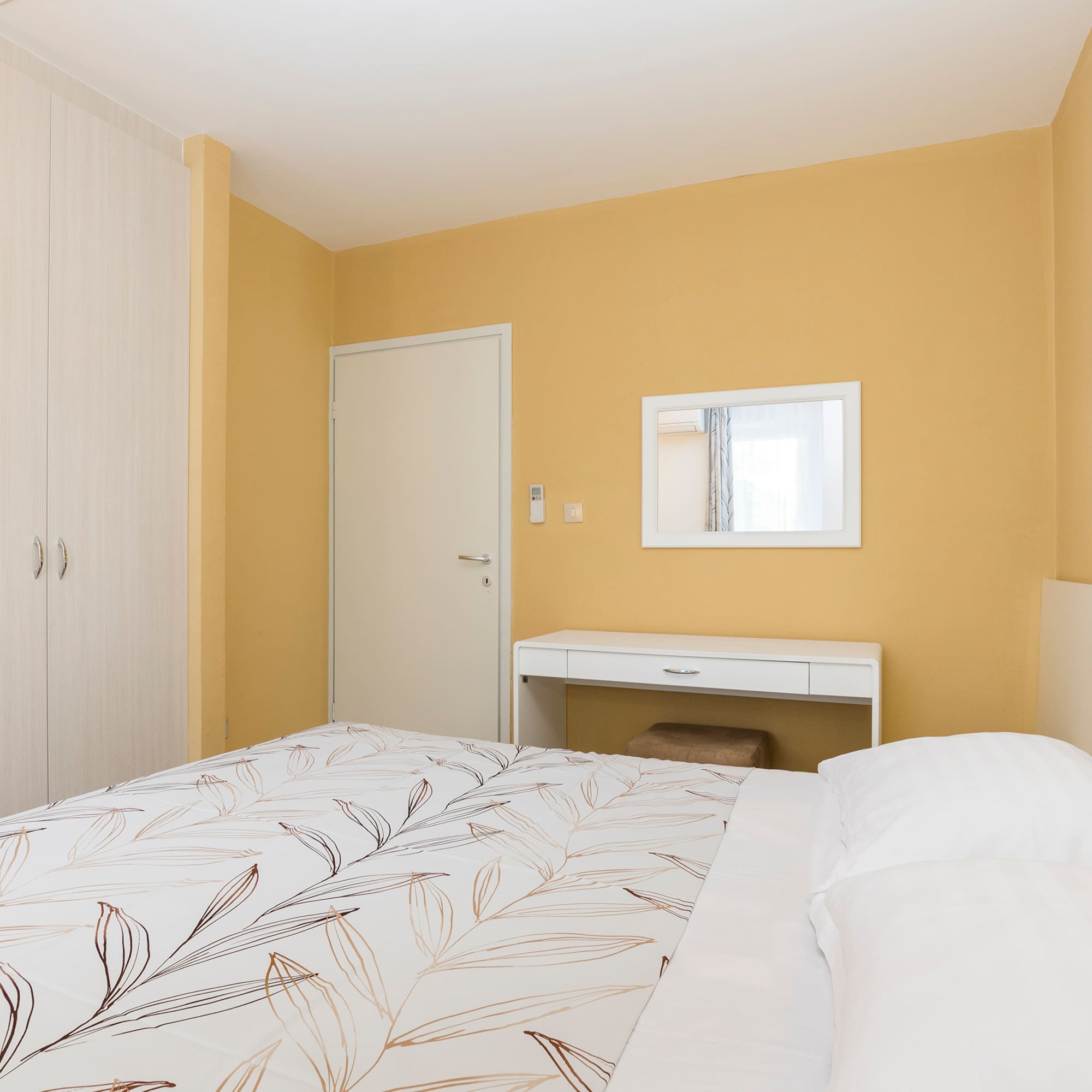a bed with a white bedding and a mirror in a room