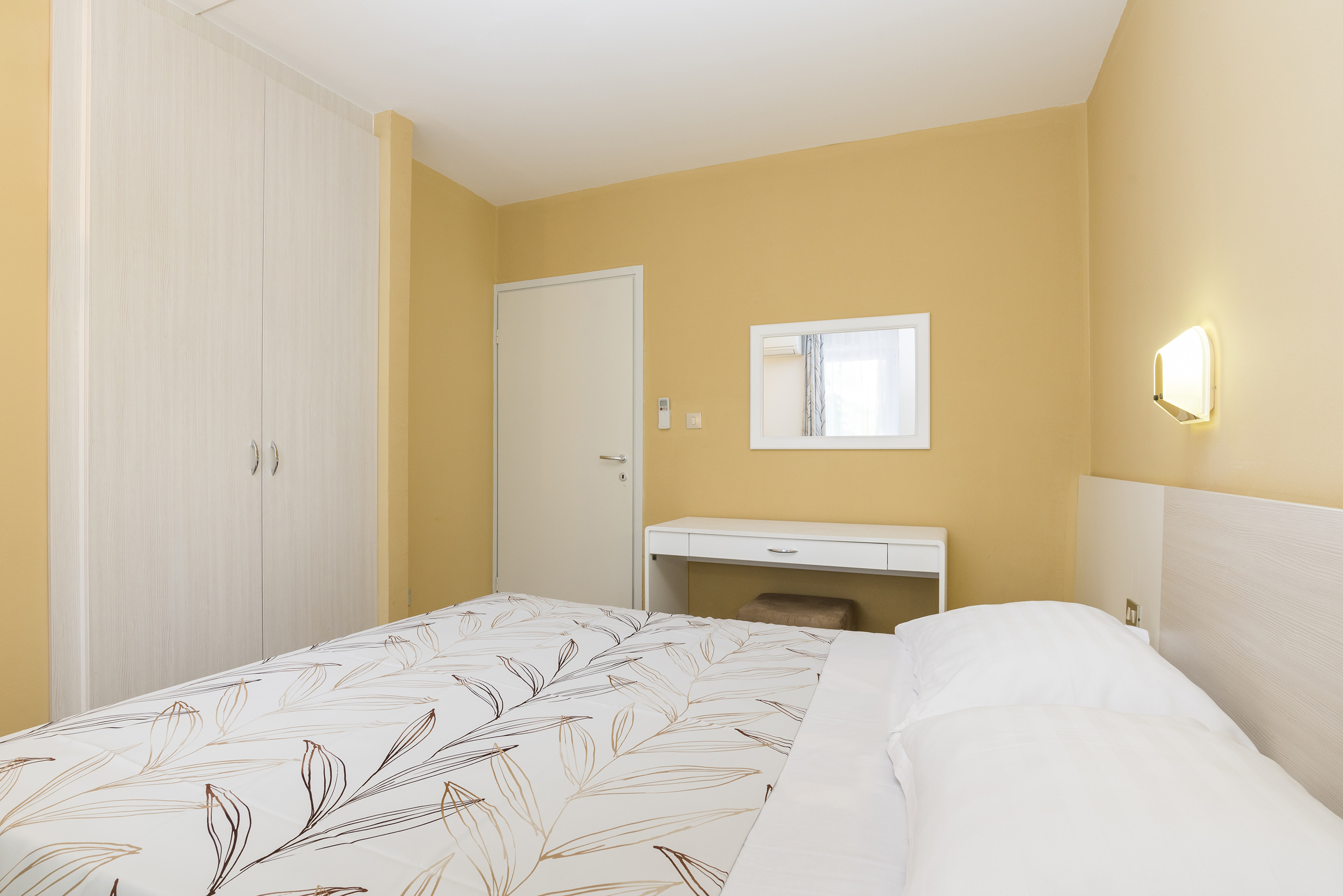 a bed with a white bedding and a mirror in a room