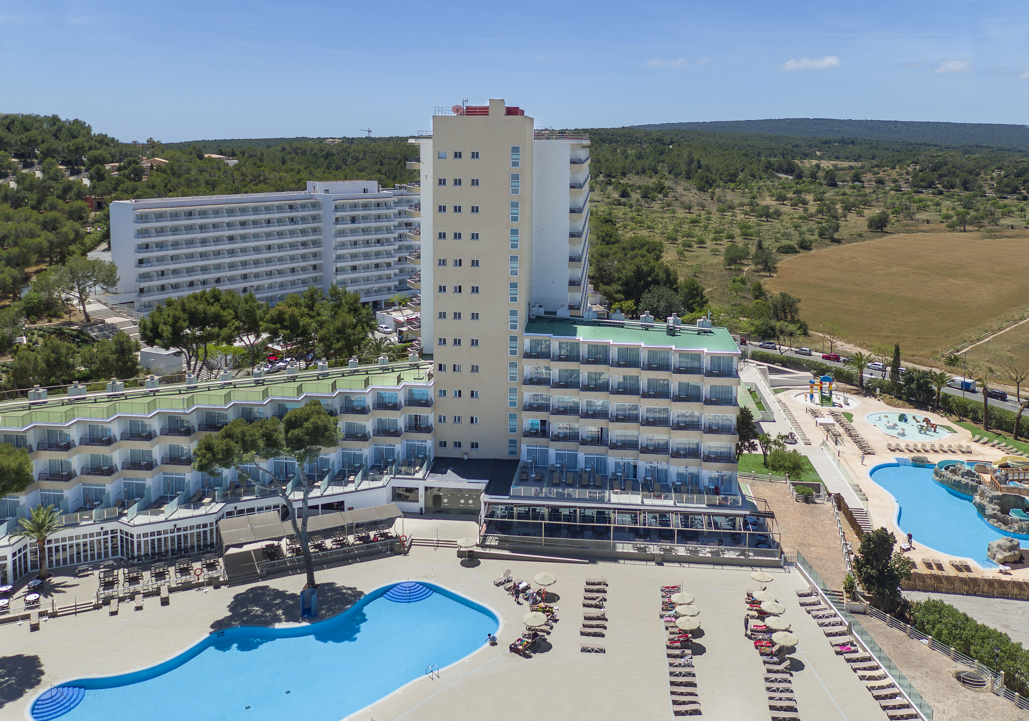 Large resort hotel with multiple buildings, swimming pools, and sun loungers.