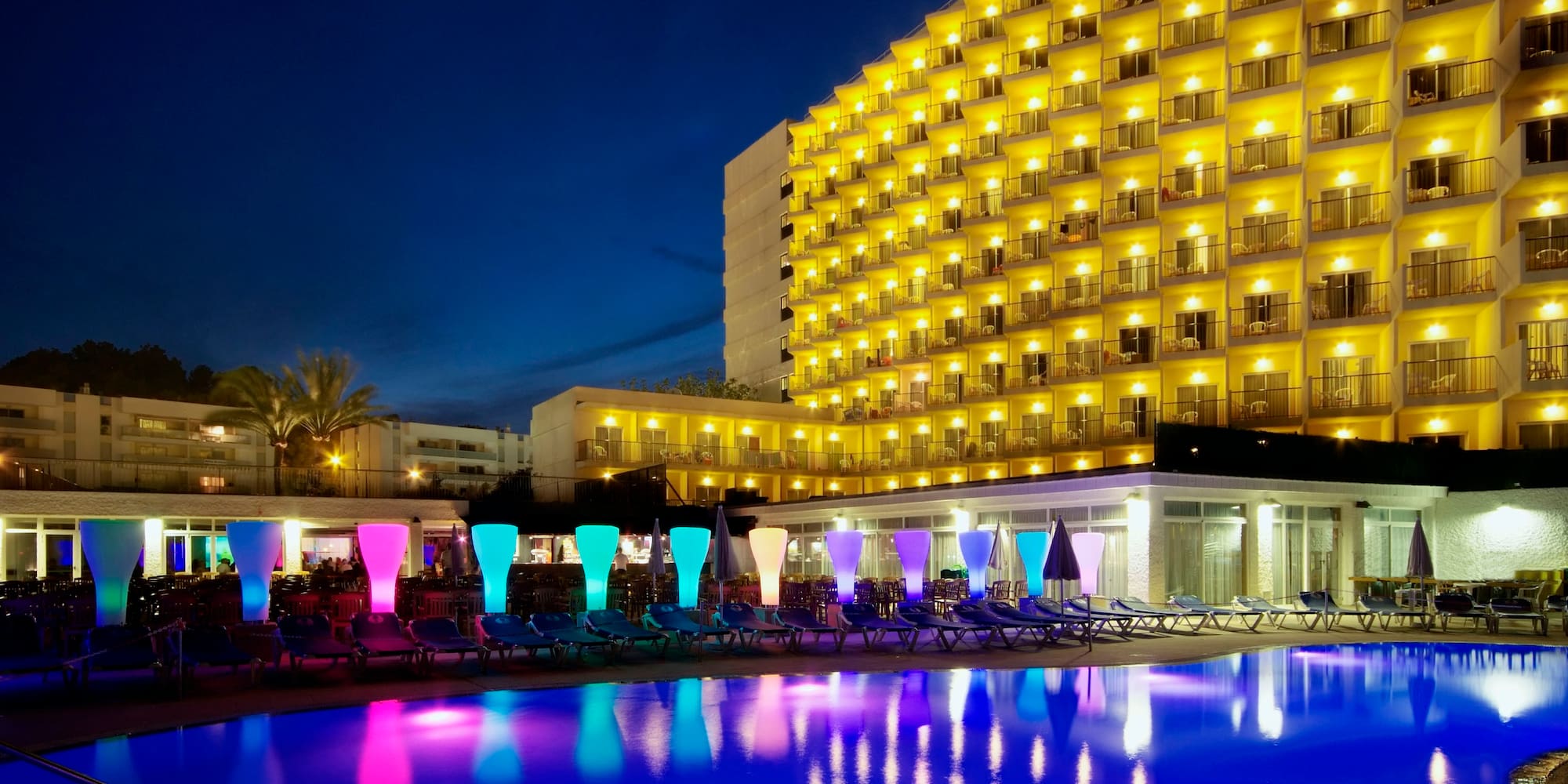 a pool with colorful lights and a building in the background