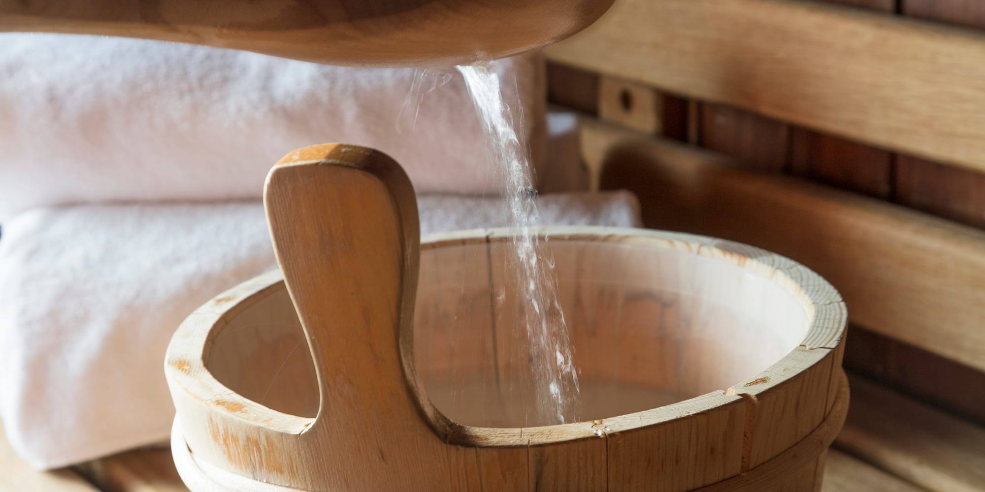 a wooden bucket with a wooden spoon pouring salt into it