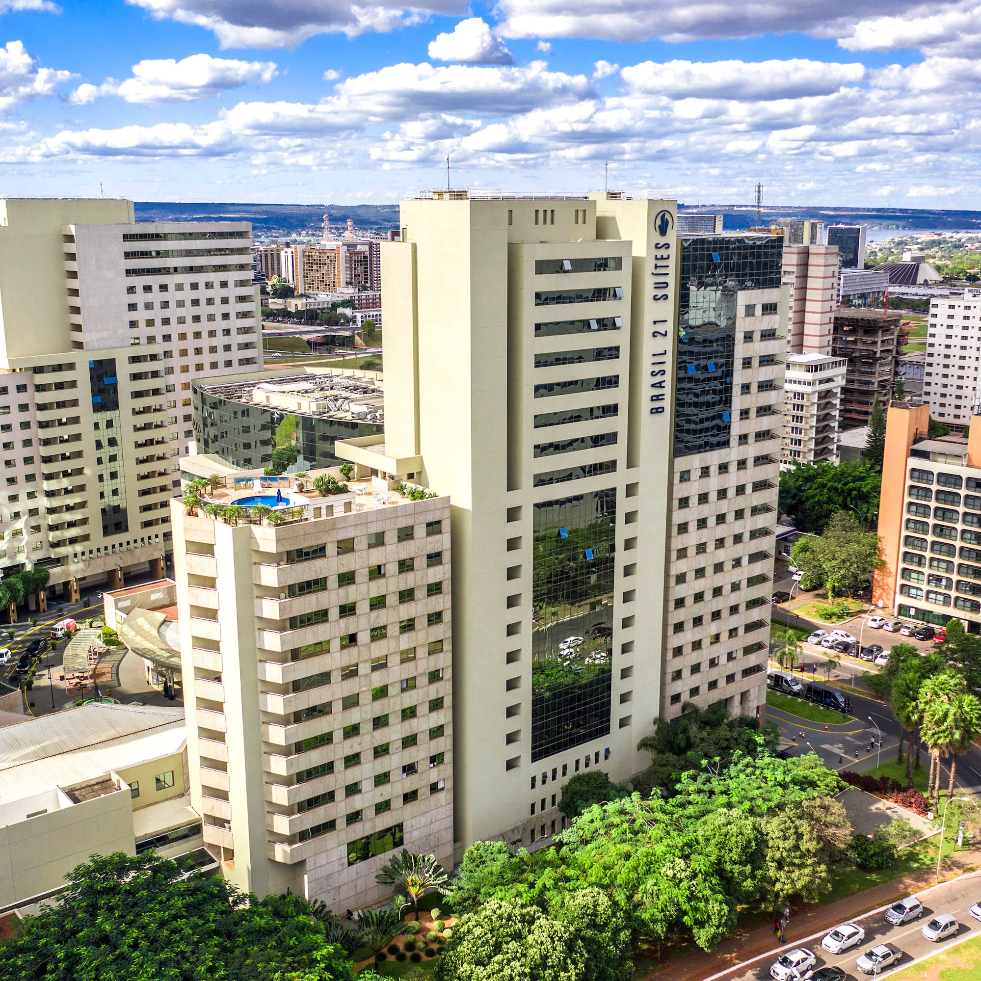 a group of tall buildings with trees and cars in the background