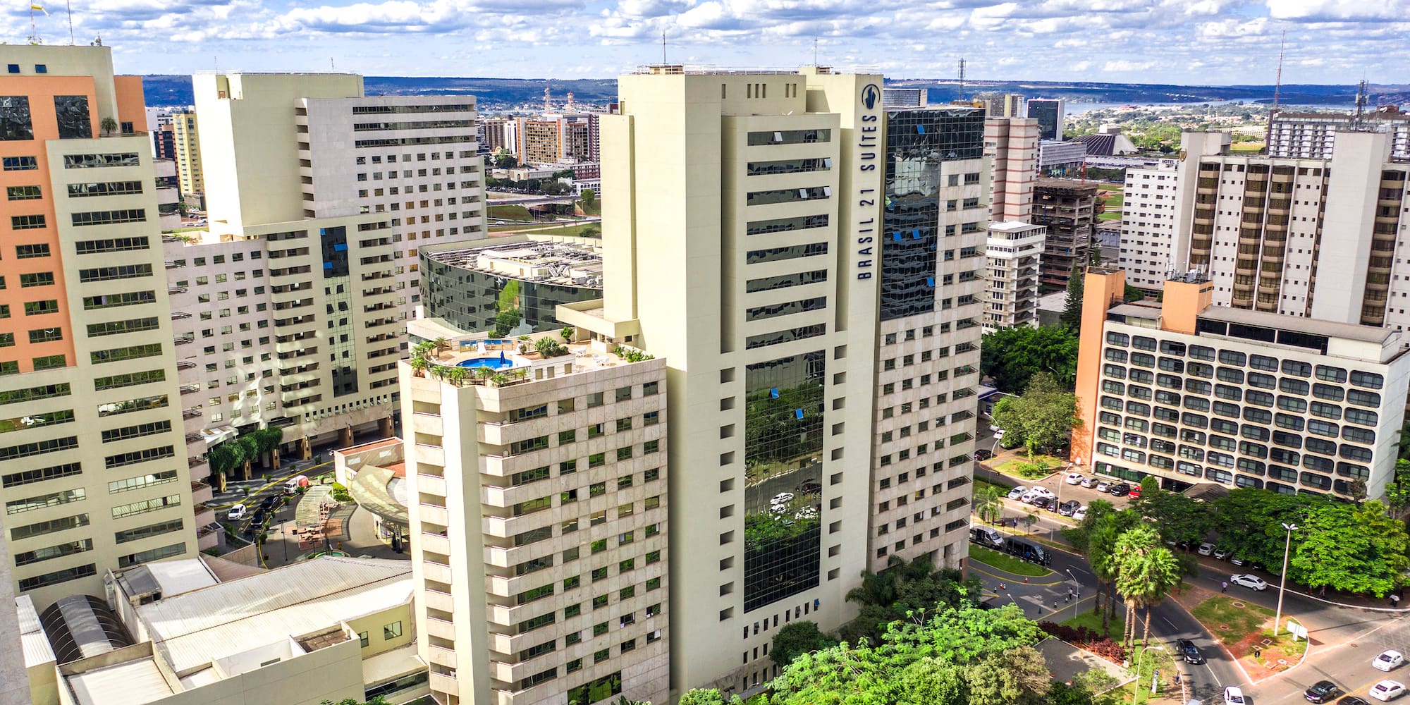 a group of tall buildings with trees and cars in the background