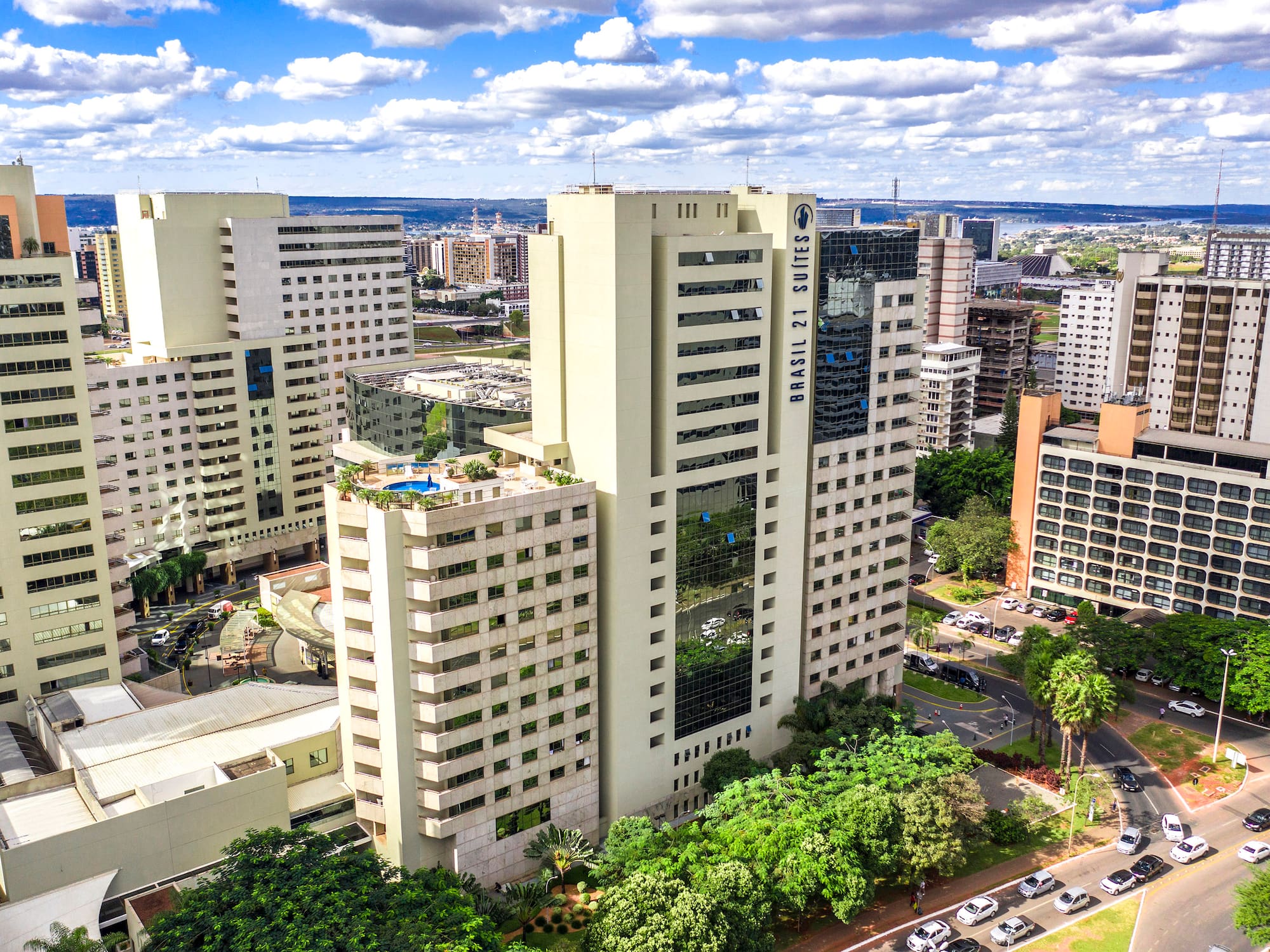a group of tall buildings with trees and cars in the background