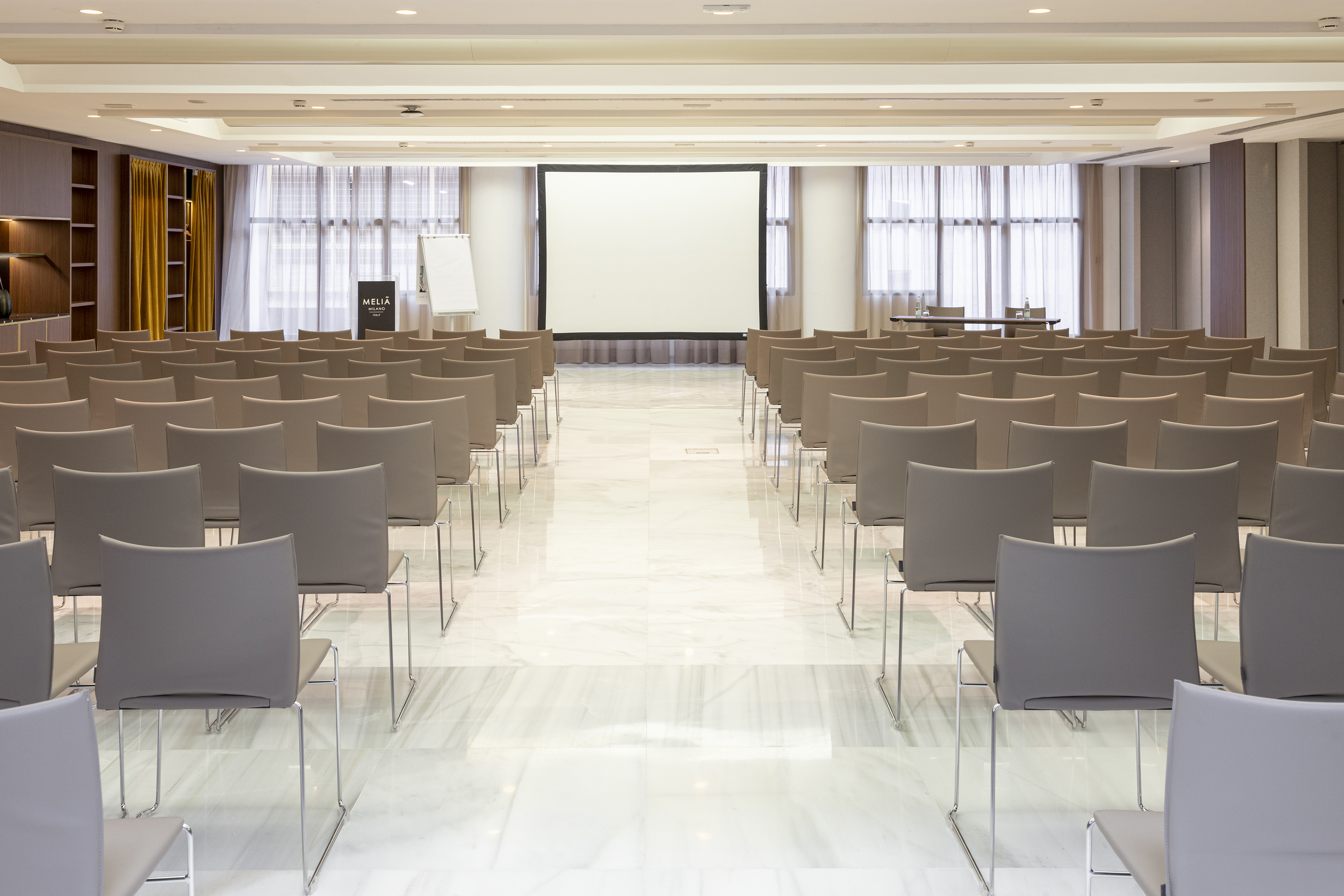 Meliá Milano conference room with rows of chairs and a large projection screen.