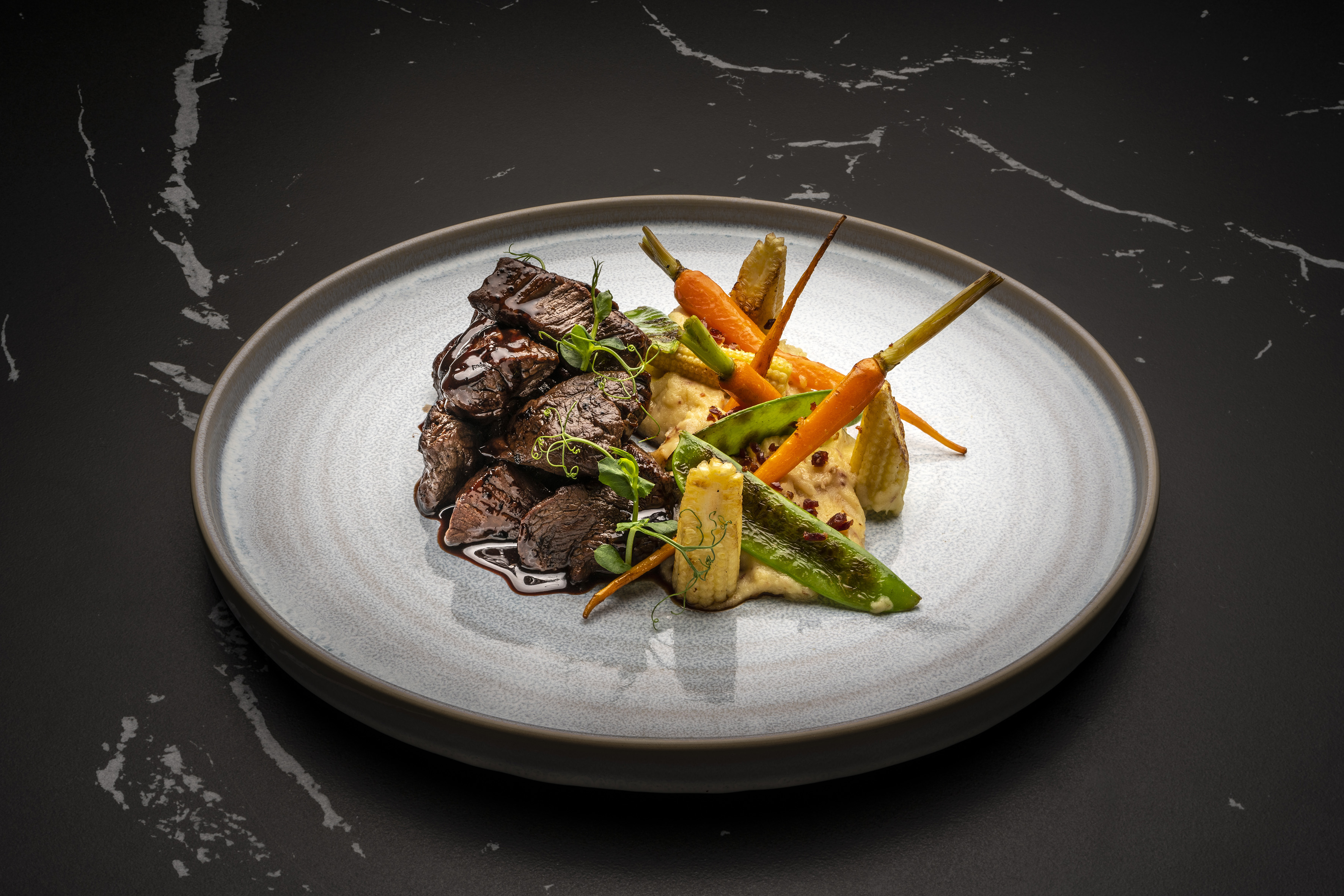 Braised beef, mashed potatoes, baby carrots, baby corn, and snap peas.