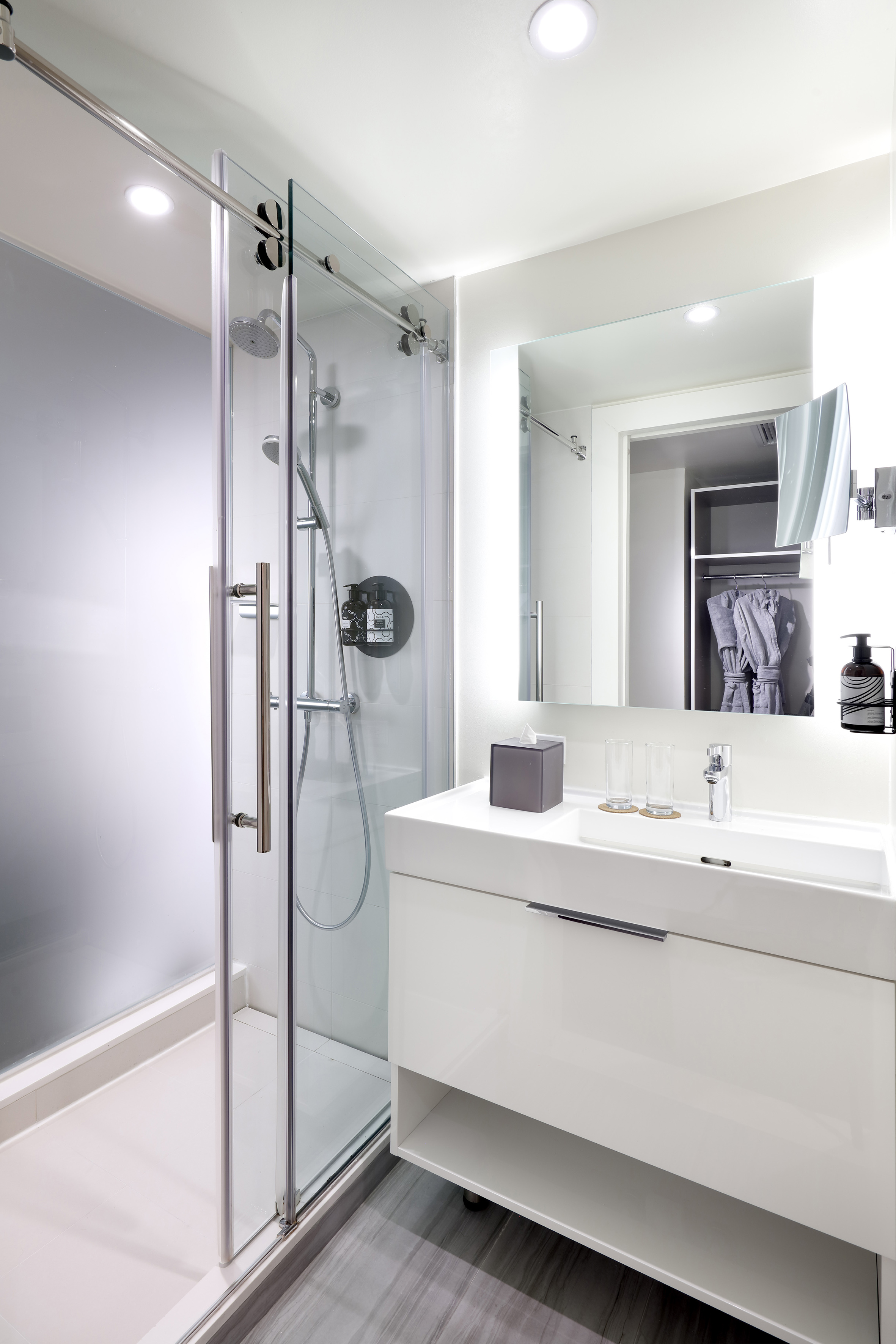 Sleek hotel bathroom with glass shower, floating vanity, and large mirror.