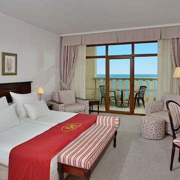 a room with a bed and chairs and a balcony